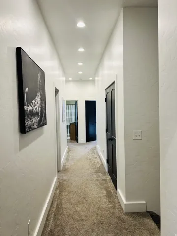 Hallway featuring recessed lighting, light-colored textured walls, and brown carpeting