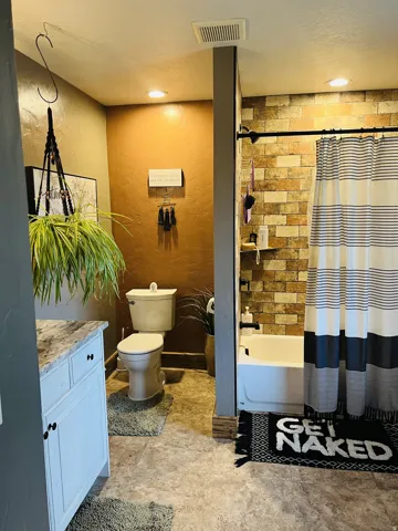 Full bathroom featuring a white vanity with a marble-look countertop, a standard toilet, and a shower-over-tub combination