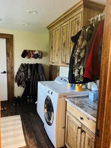 Dedicated laundry area featuring wood-finish flooring, recessed lighting, and upper and lower custom cabinetry