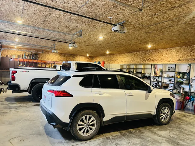 Spacious garage featuring concrete flooring, exposed oriented strand board walls and ceiling, recessed lighting, built-in shelving, and automatic garage door openers
