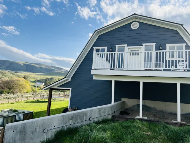 Gambrel-style residence featuring blue horizontal siding and white trim