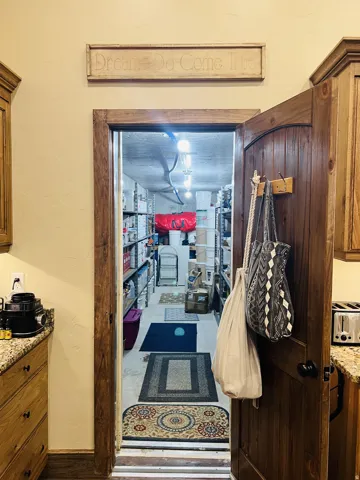 Wood-paneled door with dark hardware opens to a spacious storage area featuring extensive metal shelving