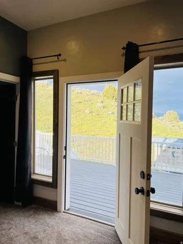Cream-painted door with divided lites opening onto a gray composite deck with white railings