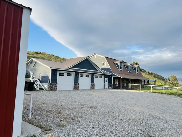 Expansive gravel driveway leading to a multi-car garage with white paneled doors