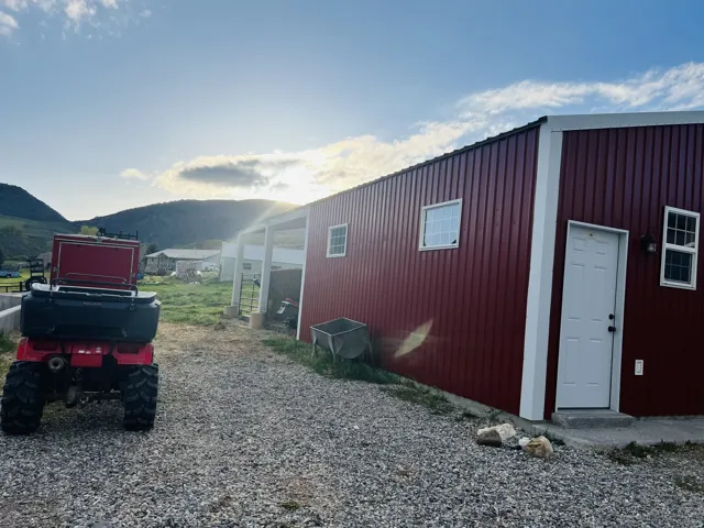 Red metal siding structure with a white exterior door and two white-framed windows