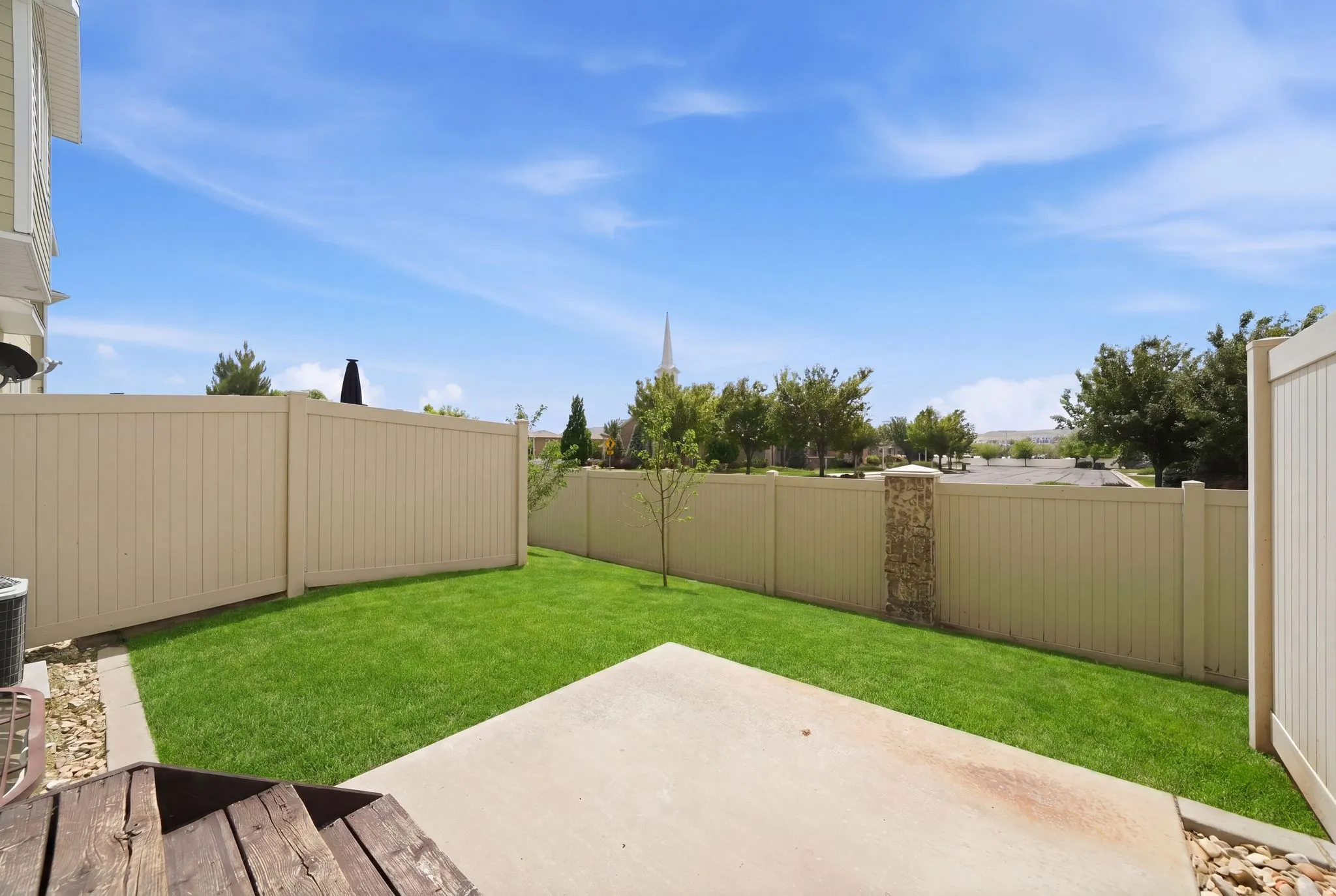 Expansive backyard featuring a manicured lawn, concrete patio, and full perimeter fencing