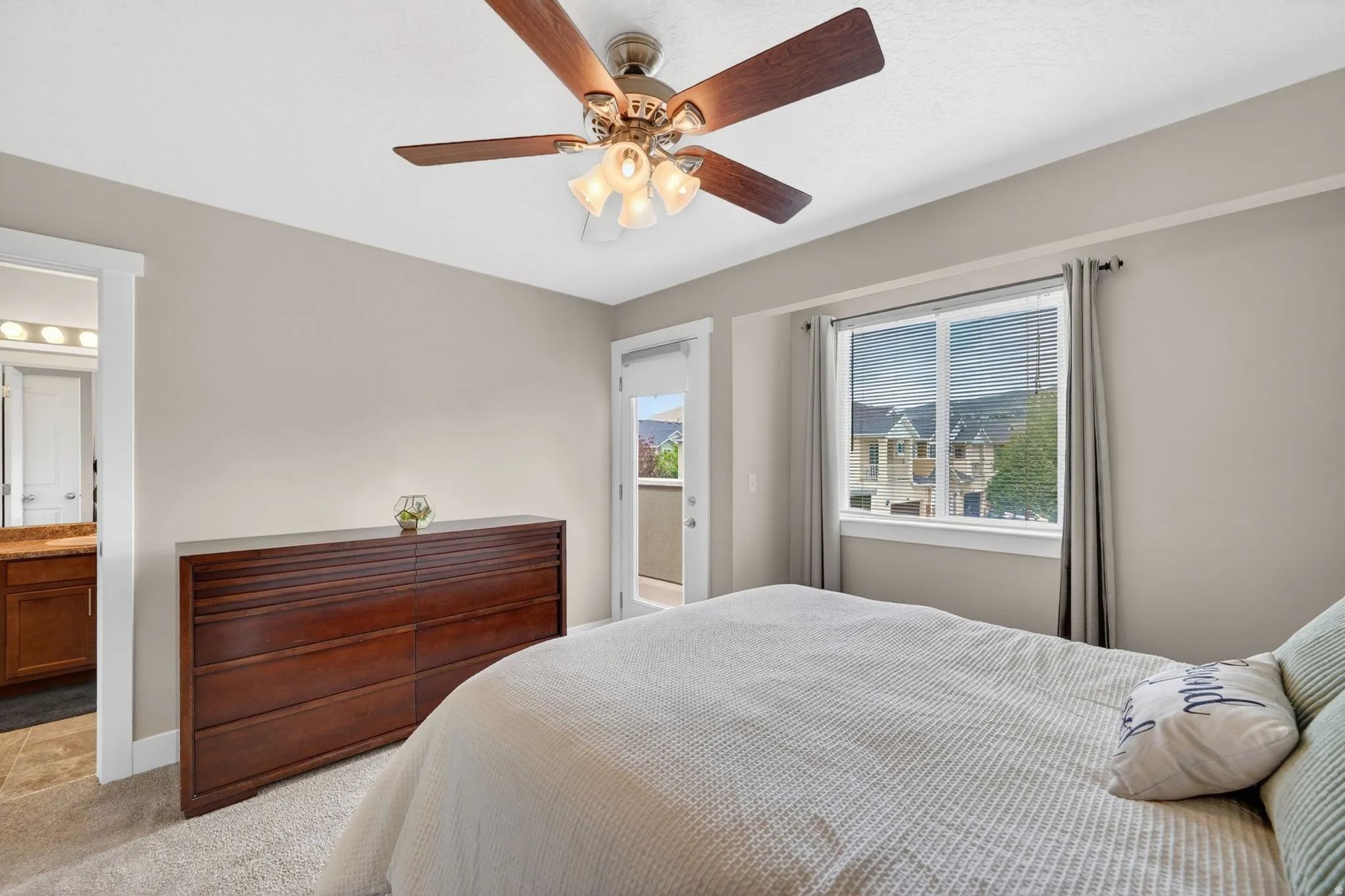 Bedroom with light neutral wall paint, carpet flooring, and a ceiling fan with integrated lighting