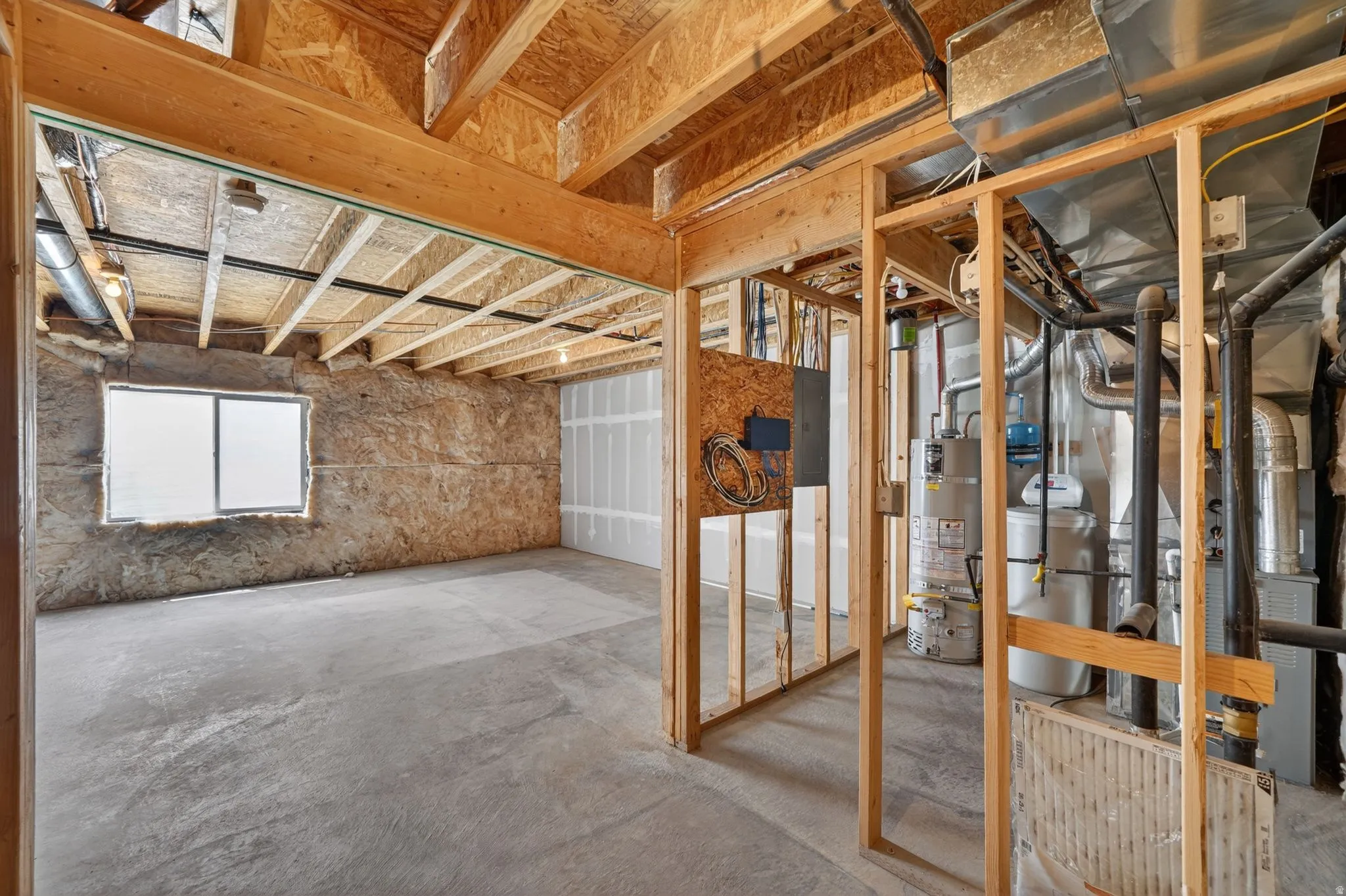 Unfinished basement space featuring exposed wood framing, concrete flooring, and a single window
