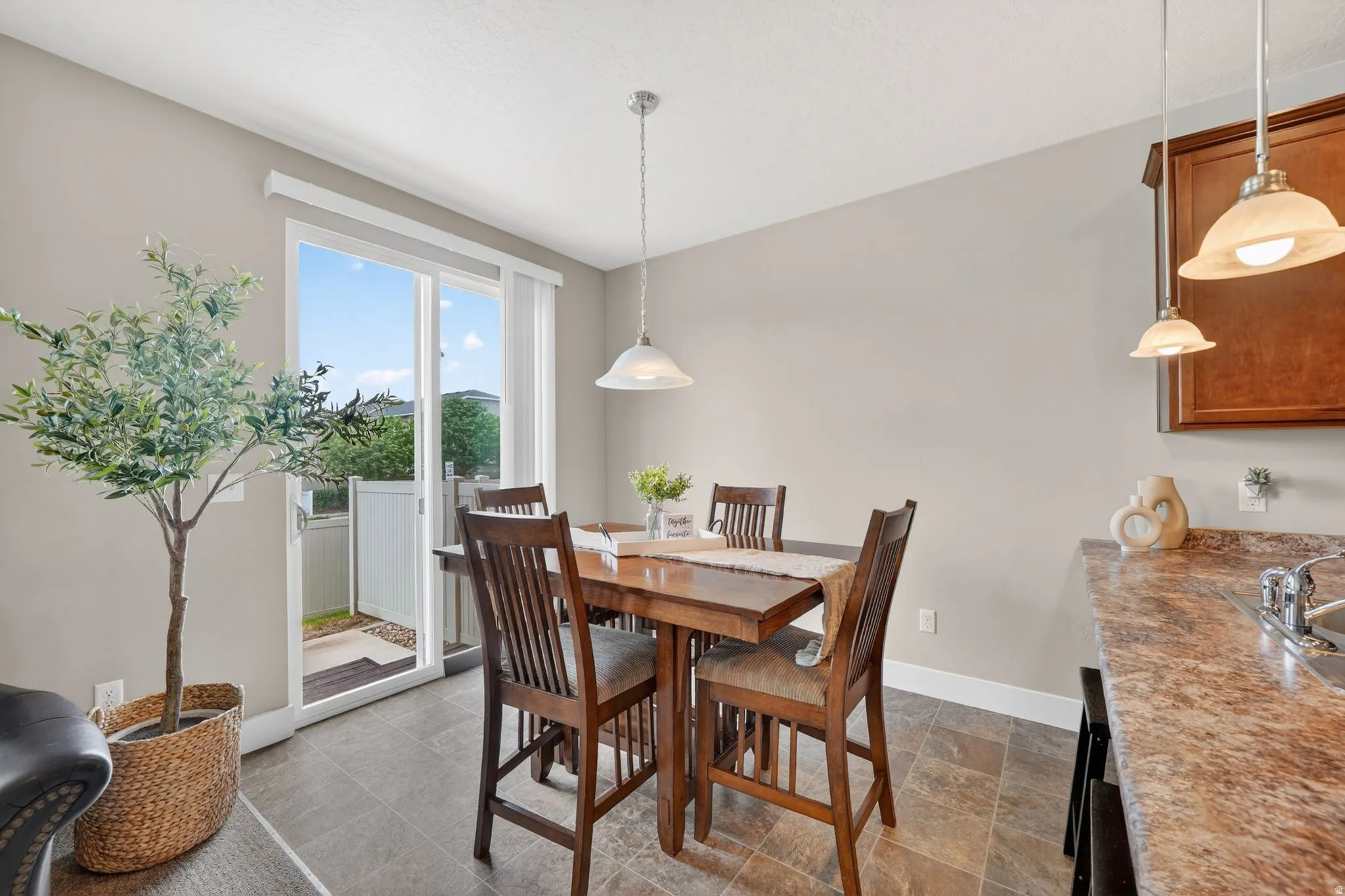 Dining area featuring a wood-finish table and chairs, pendant lighting, and tiled flooring
