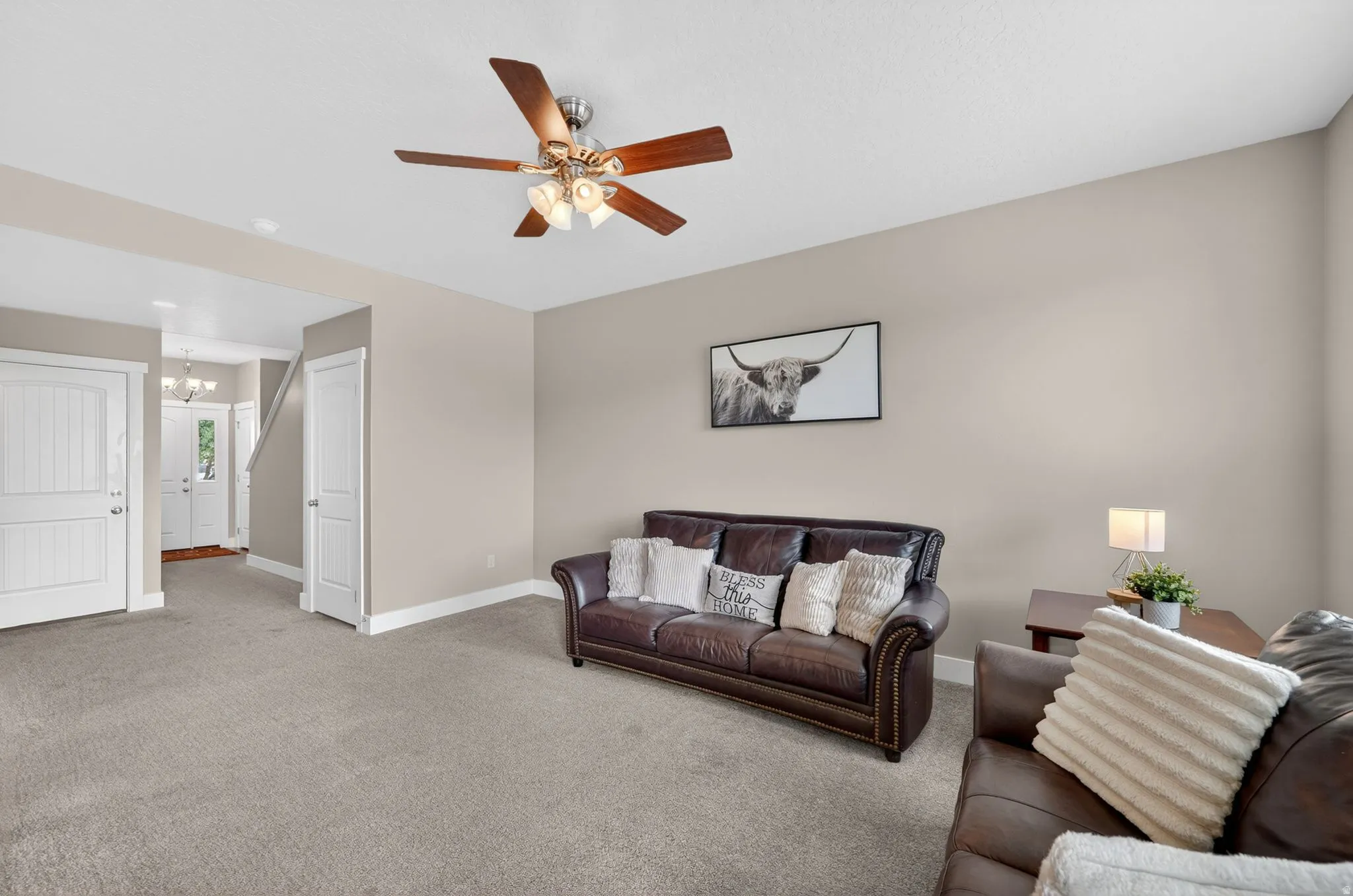Carpeted living area with neutral wall tones and a ceiling fan with integrated lighting