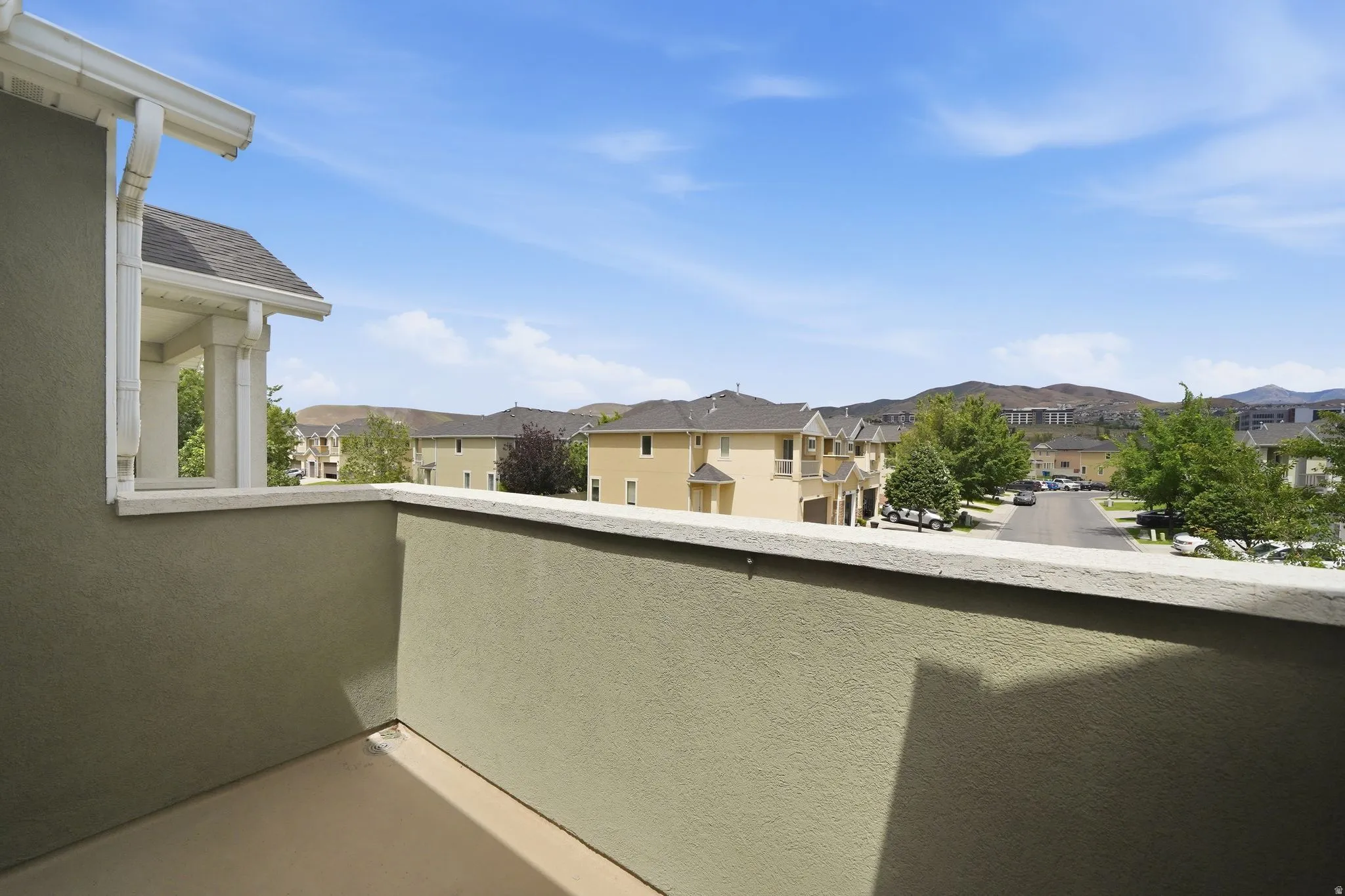 Private outdoor balcony with stucco exterior and concrete flooring, offering open-air access