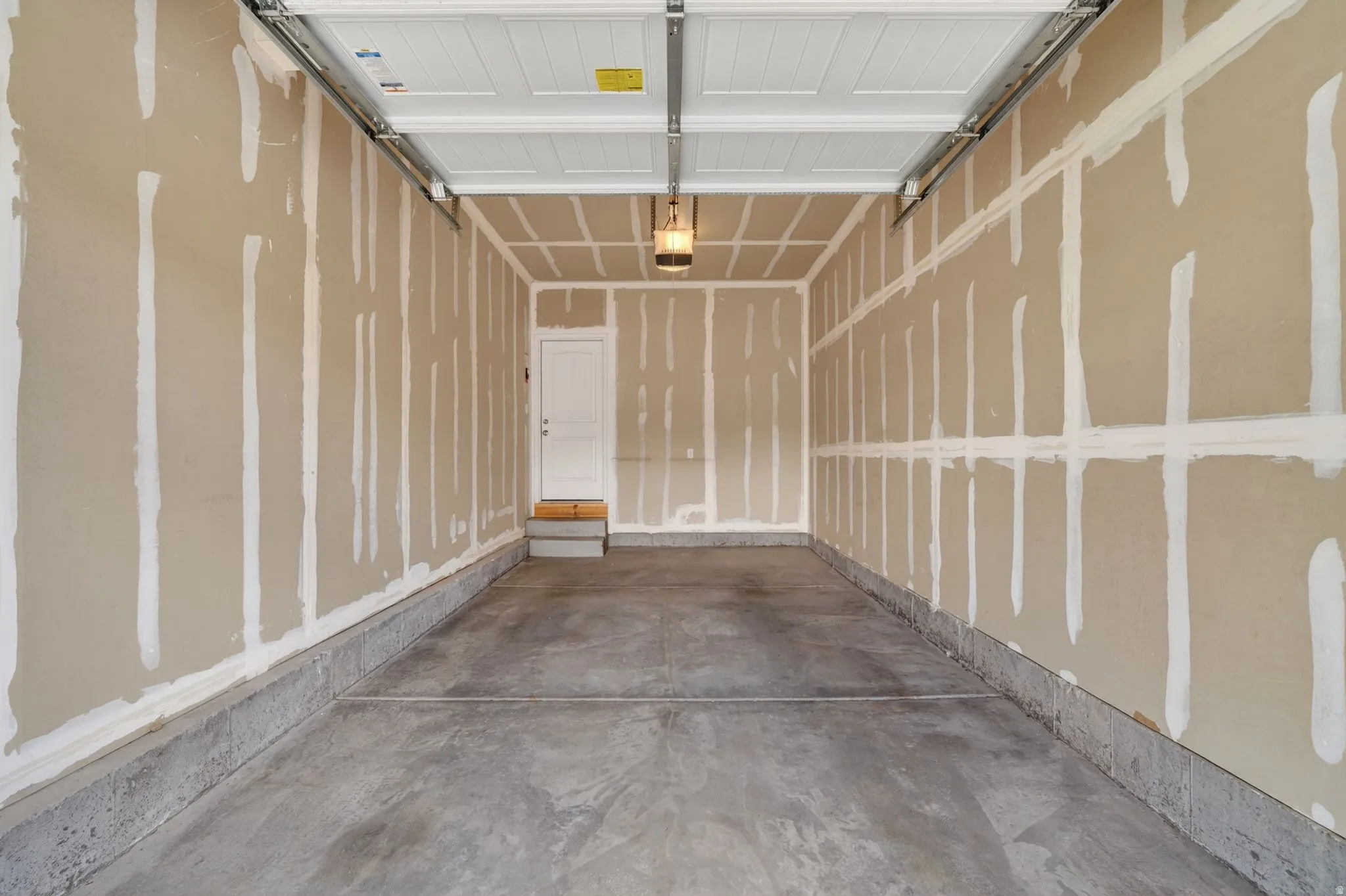 Spacious garage featuring a concrete floor, overhead lighting, and an interior access door
