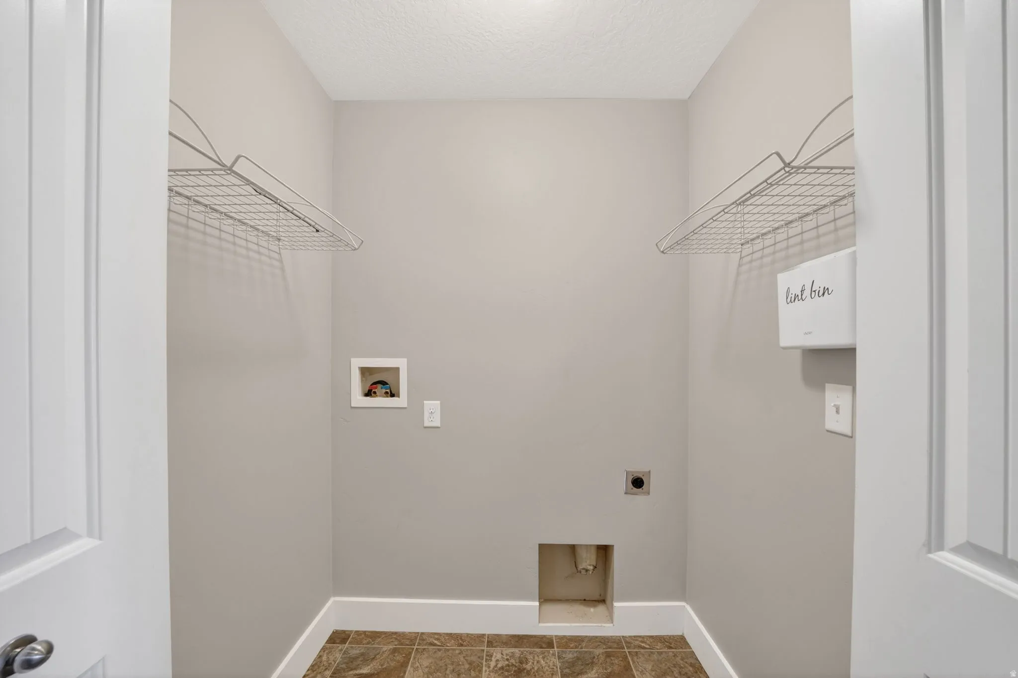Dedicated utility space featuring neutral wall tones and durable tile flooring
