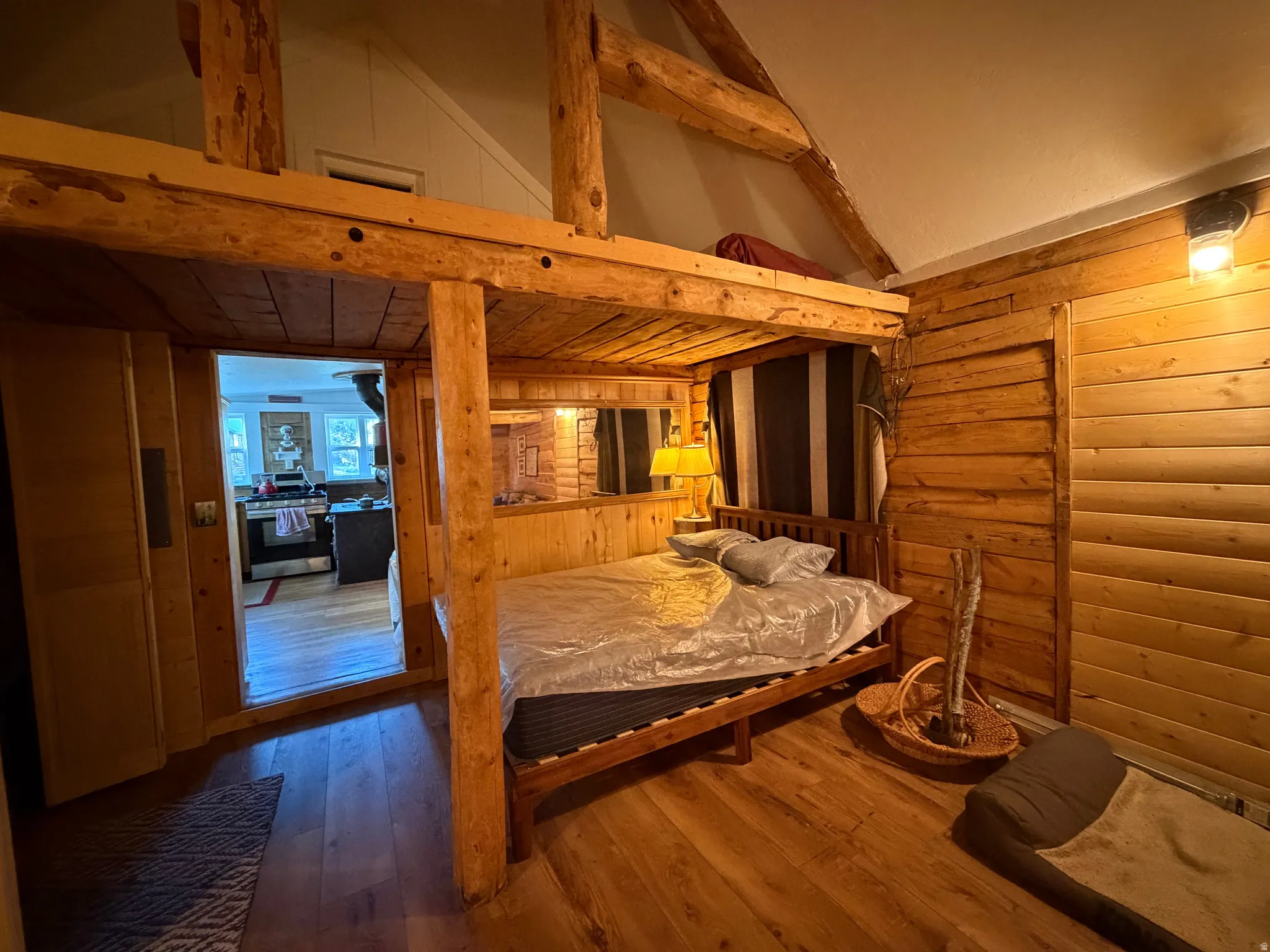 Wood-finish flooring throughout, featuring a built-in wooden bed frame and a rustic wood-plank wall