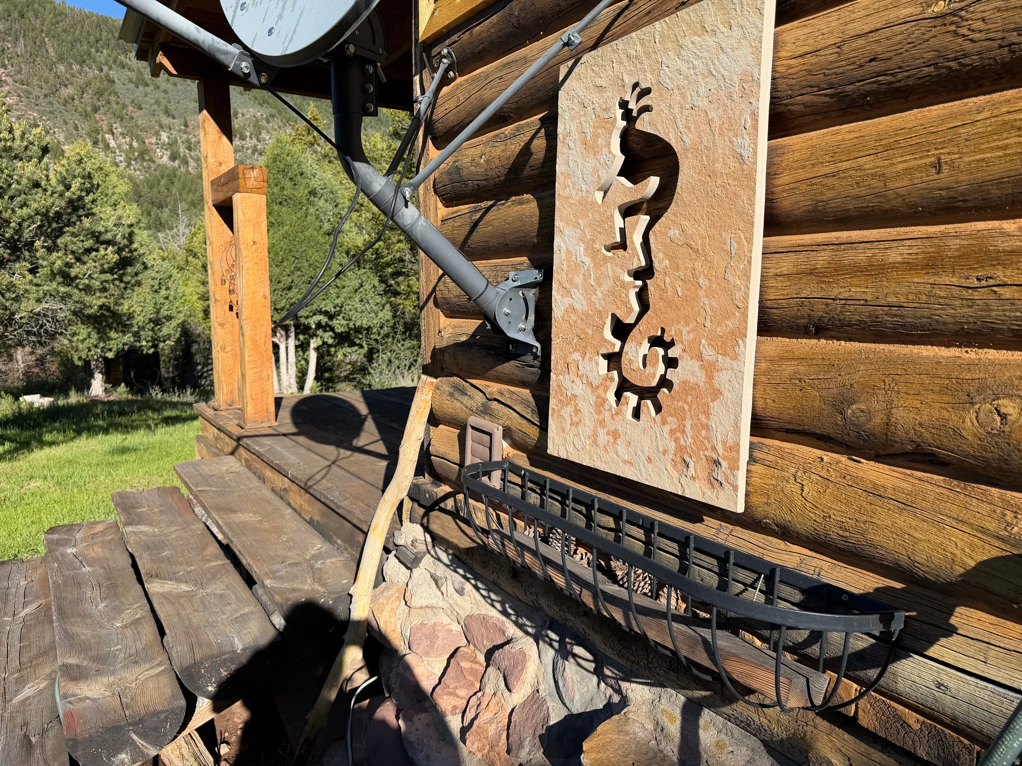Log cabin exterior featuring a rock-faced foundation, natural wood porch posts, and wood plank stairs