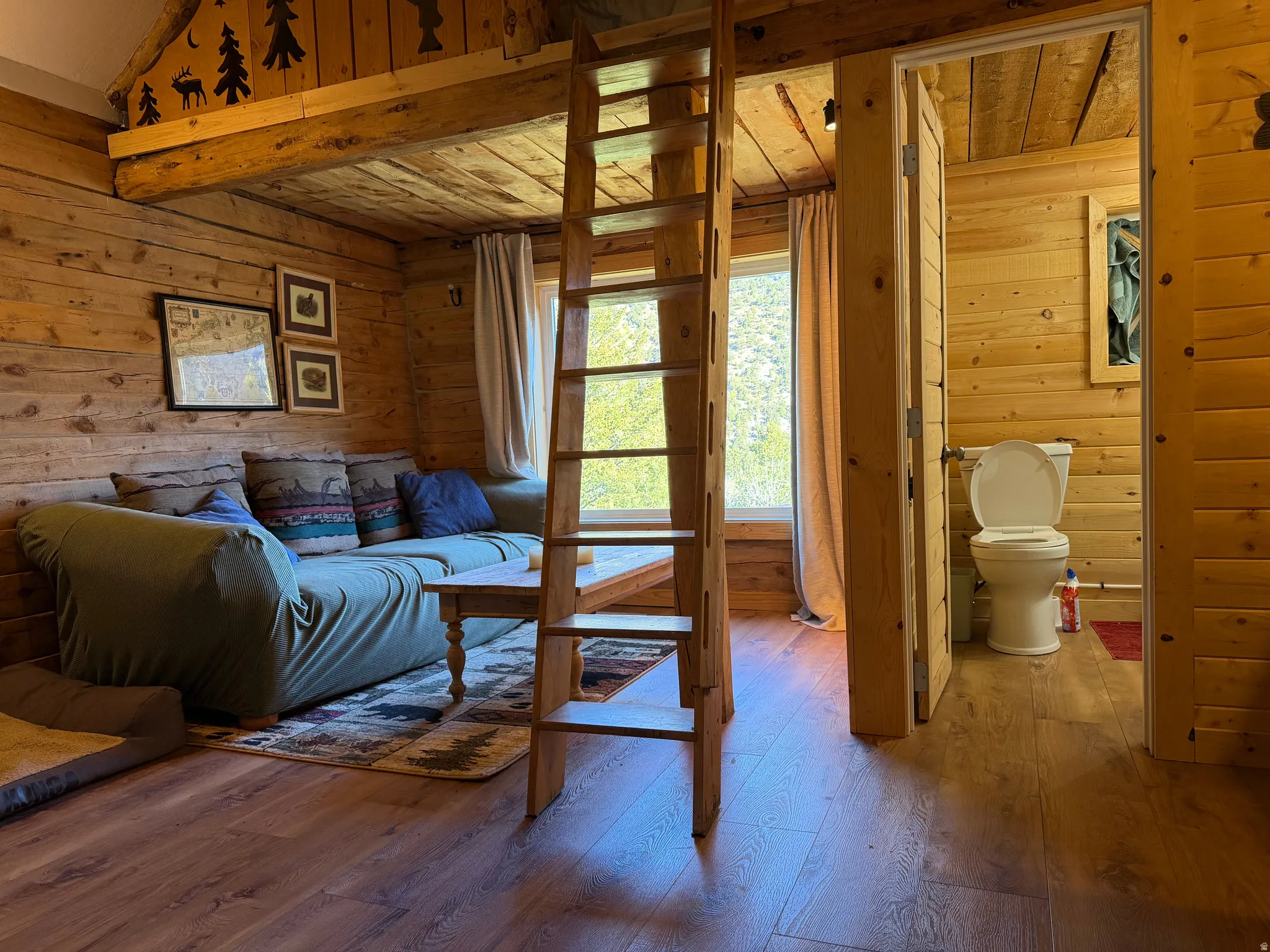 Interiors featuring wood-finish flooring, exposed wood beam ceiling, a wooden ladder, and natural wood plank walls