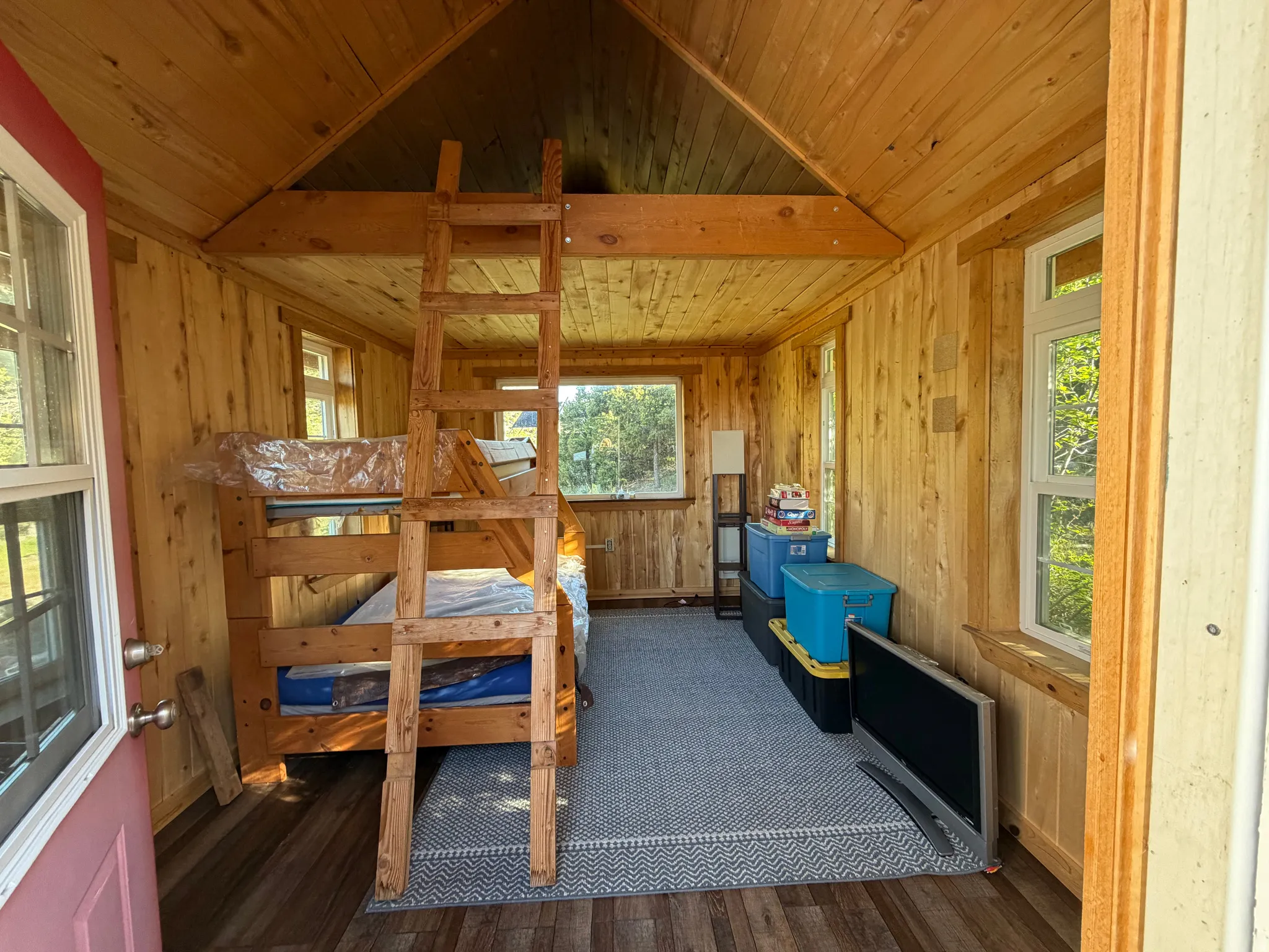 Interior space featuring wood-paneled walls and ceiling, wood-finish flooring, and multiple windows