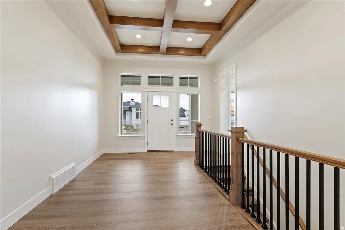 Entryway featuring a coffered ceiling with recessed lighting, LVP flooring, and a wood railing with black iron balusters