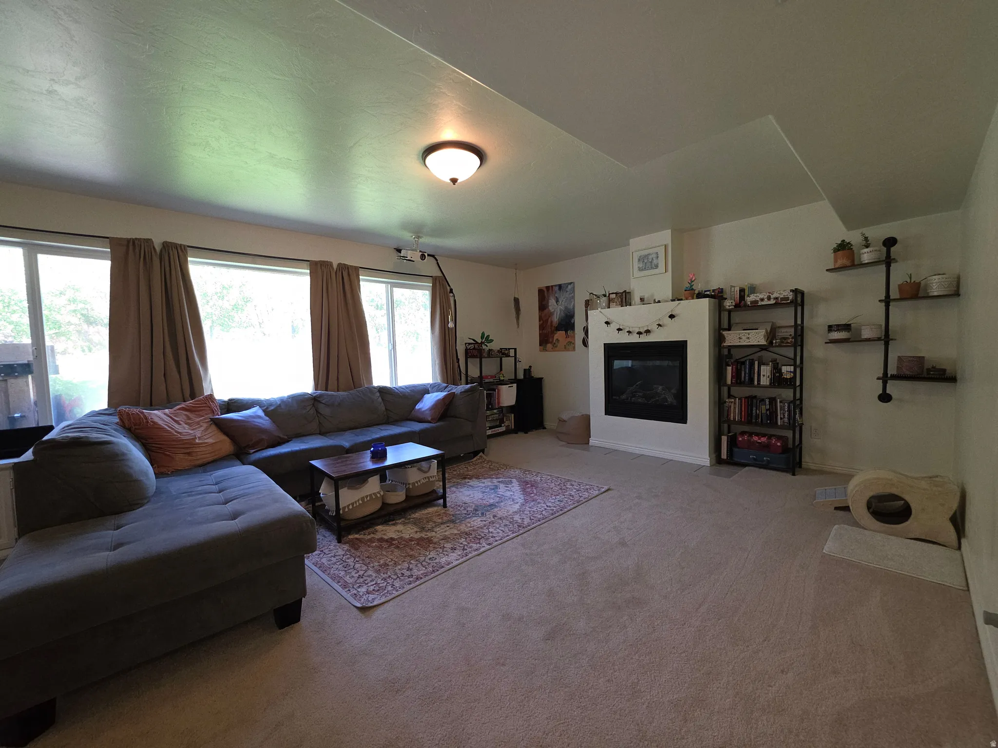 Spacious living area featuring ample natural light from multiple windows, a built-in fireplace, recessed ceiling, and carpeted flooring