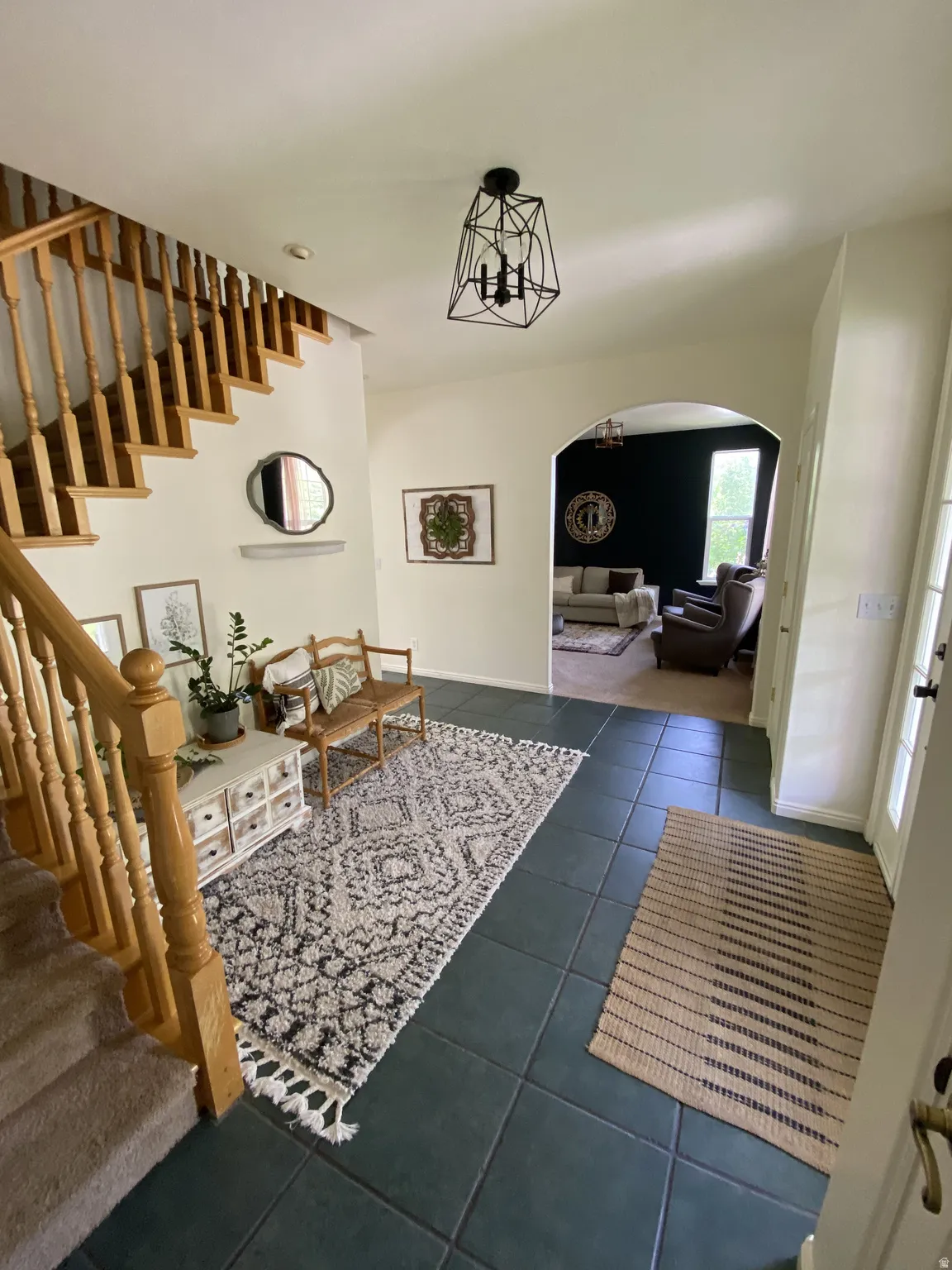 Spacious entryway featuring dark tile flooring and a light wood staircase with balusters
