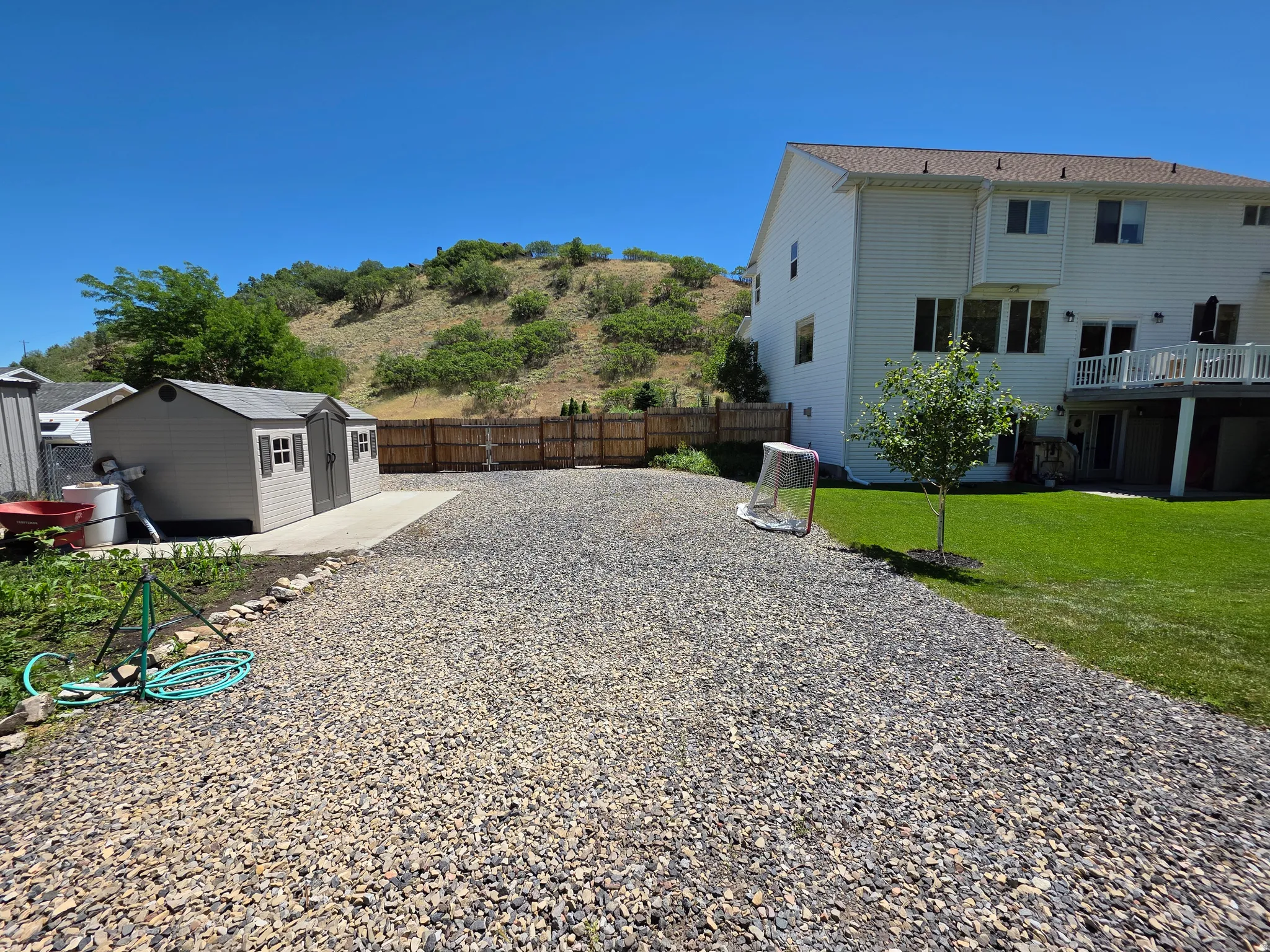 Expansive gravel area with a dedicated concrete pad and storage shed