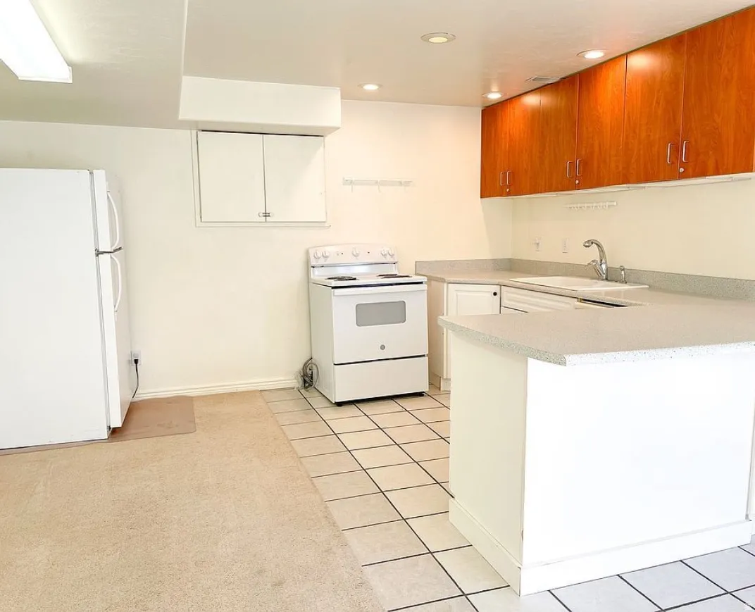 2nd kitchen for ADU featuring white appliances, upper wood-finish cabinetry, a built-in sink, and speckled countertops