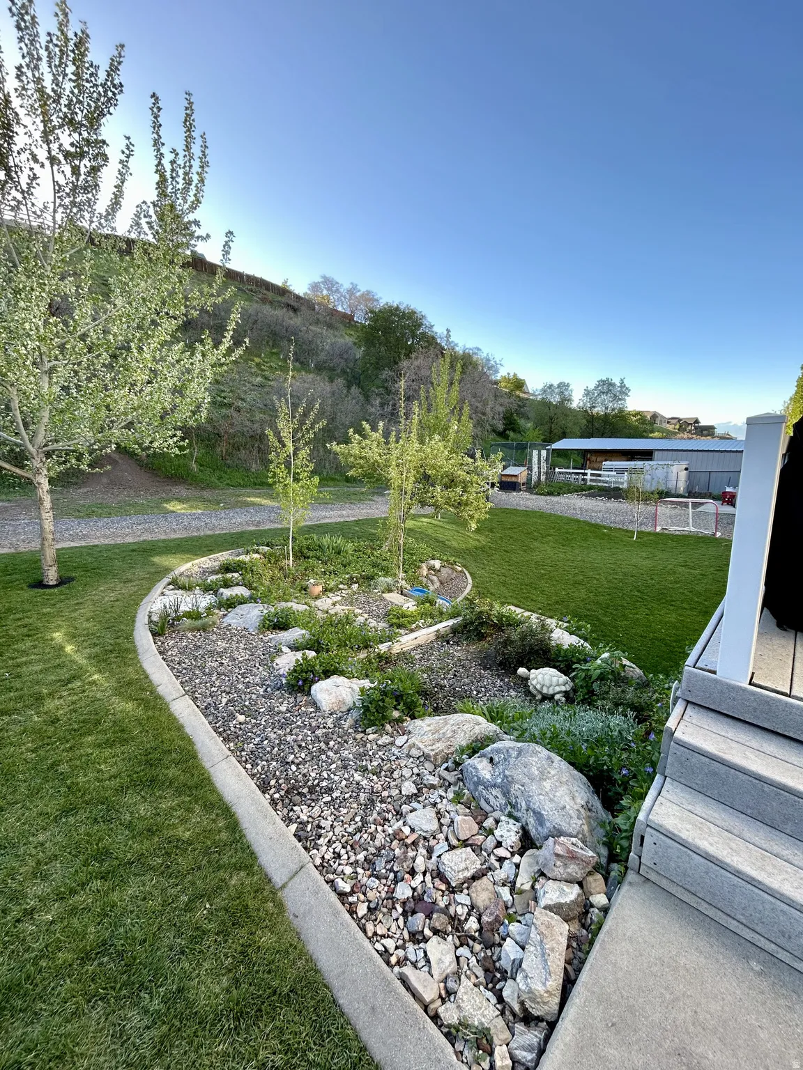 Expansive lawn with a decorative rock garden featuring varied plantings