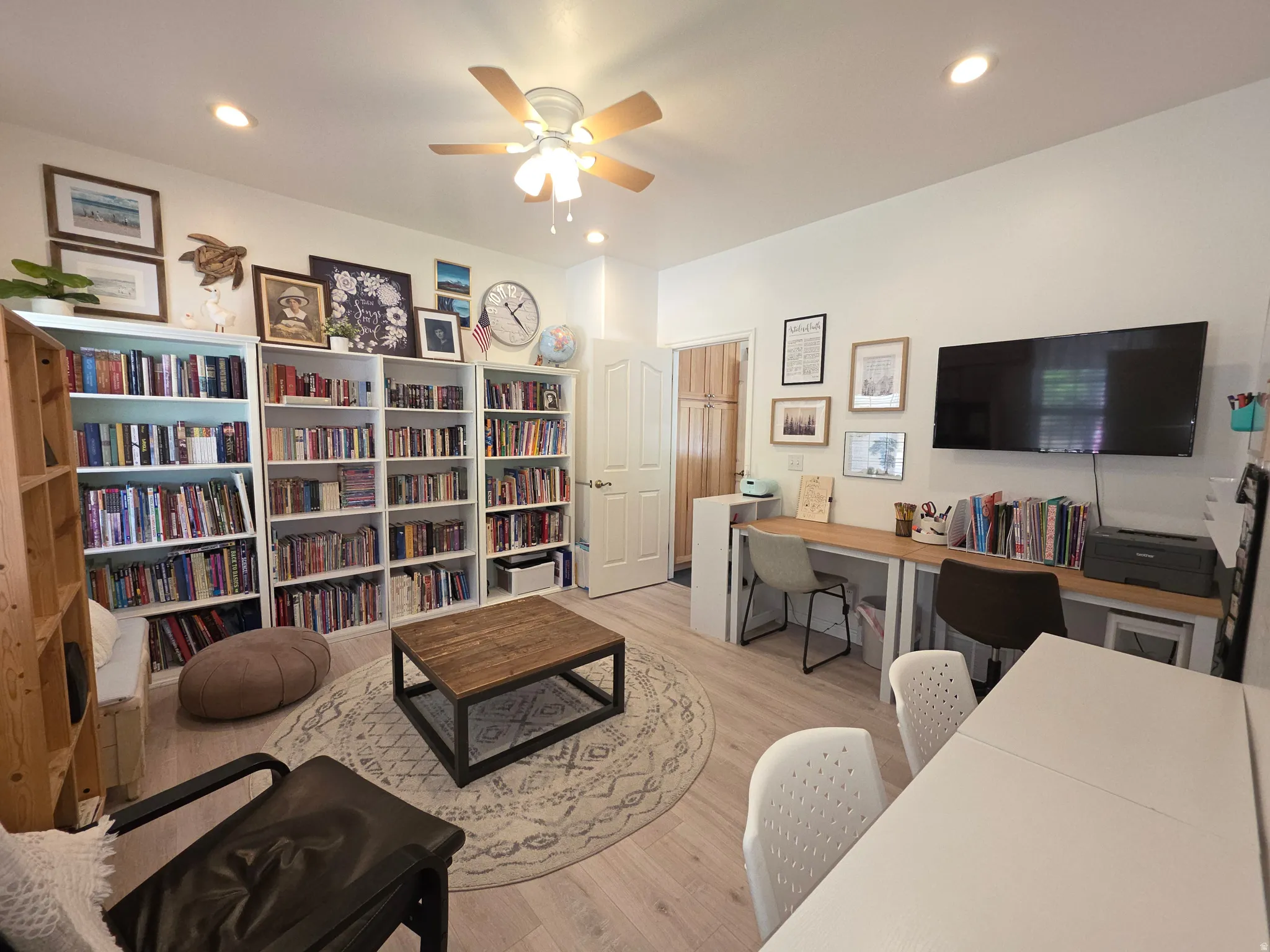Versatile room featuring extensive built-in shelving, light wood-finish flooring, and recessed lighting