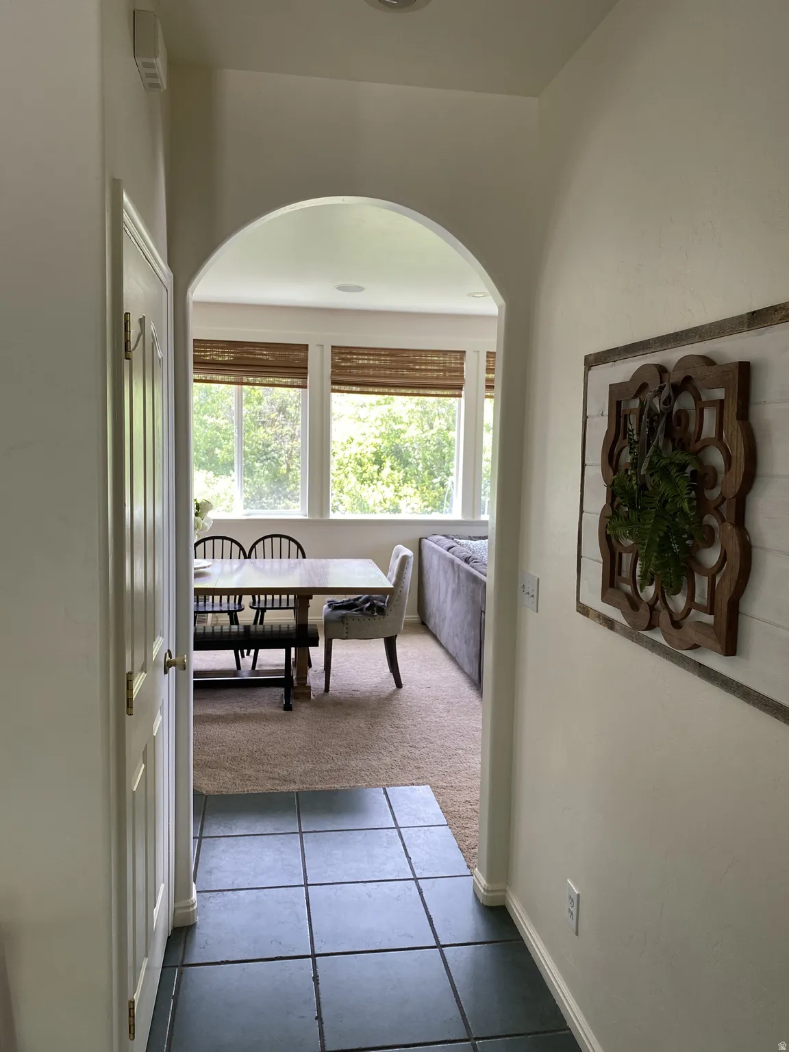 Arched doorway entry to an interior space featuring a wall of windows, carpeted flooring, and recessed lighting