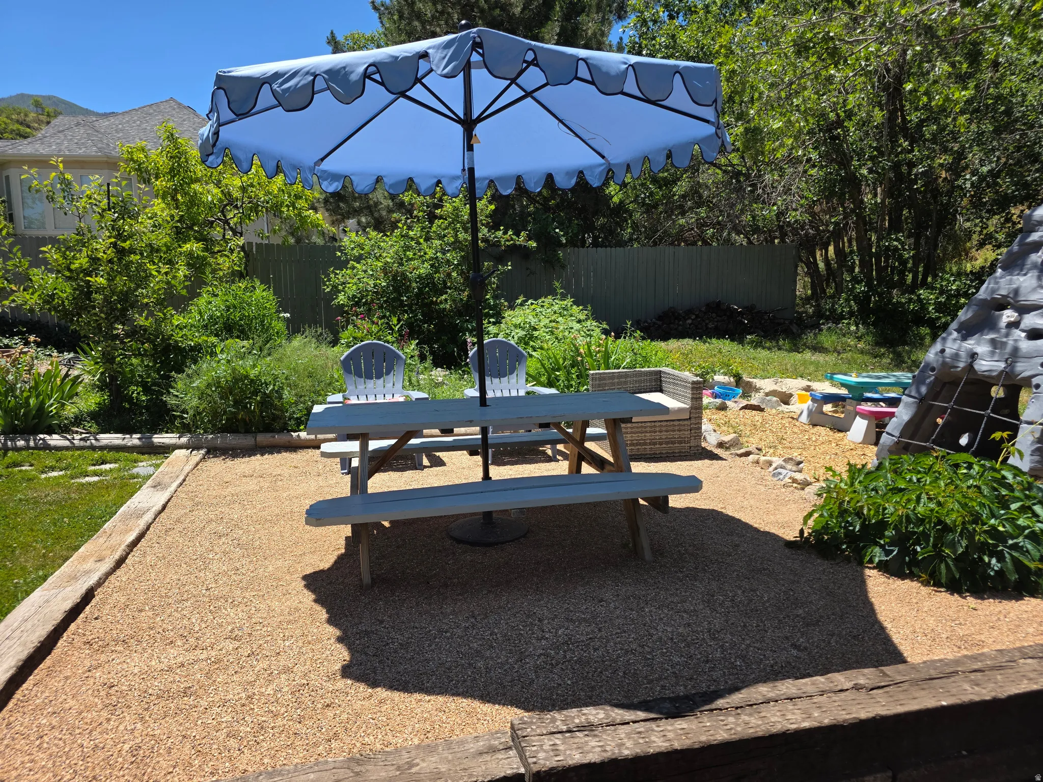 Gravel patio area with a picnic table and surrounding mature landscaping