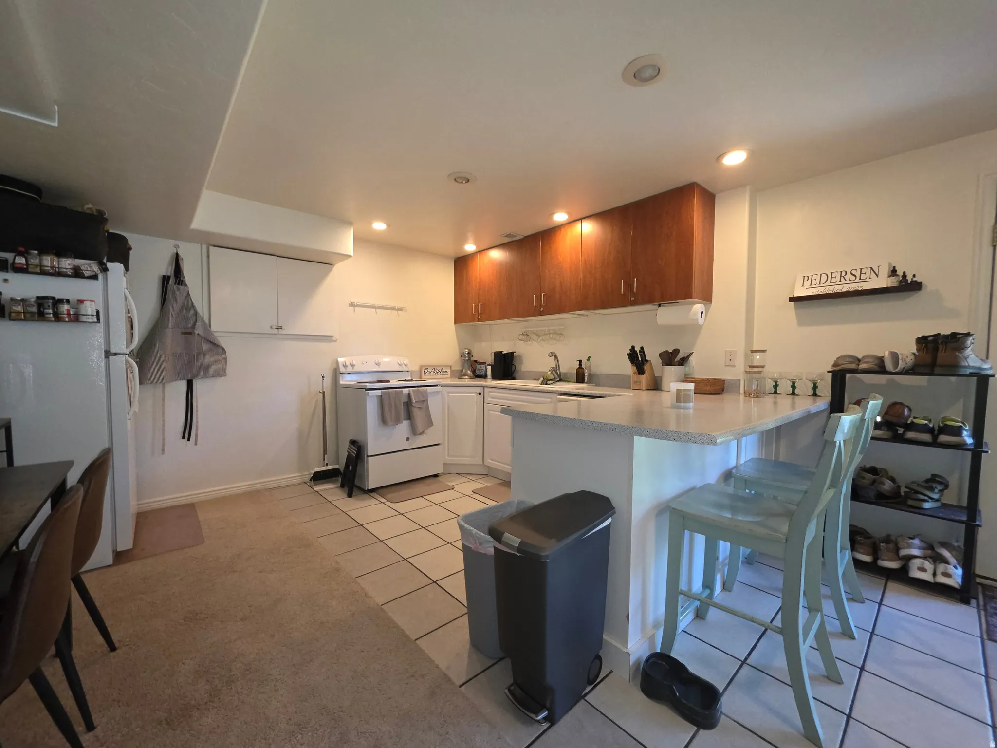 Kitchen featuring wood-finish upper cabinetry, white lower cabinetry, and a white appliance package