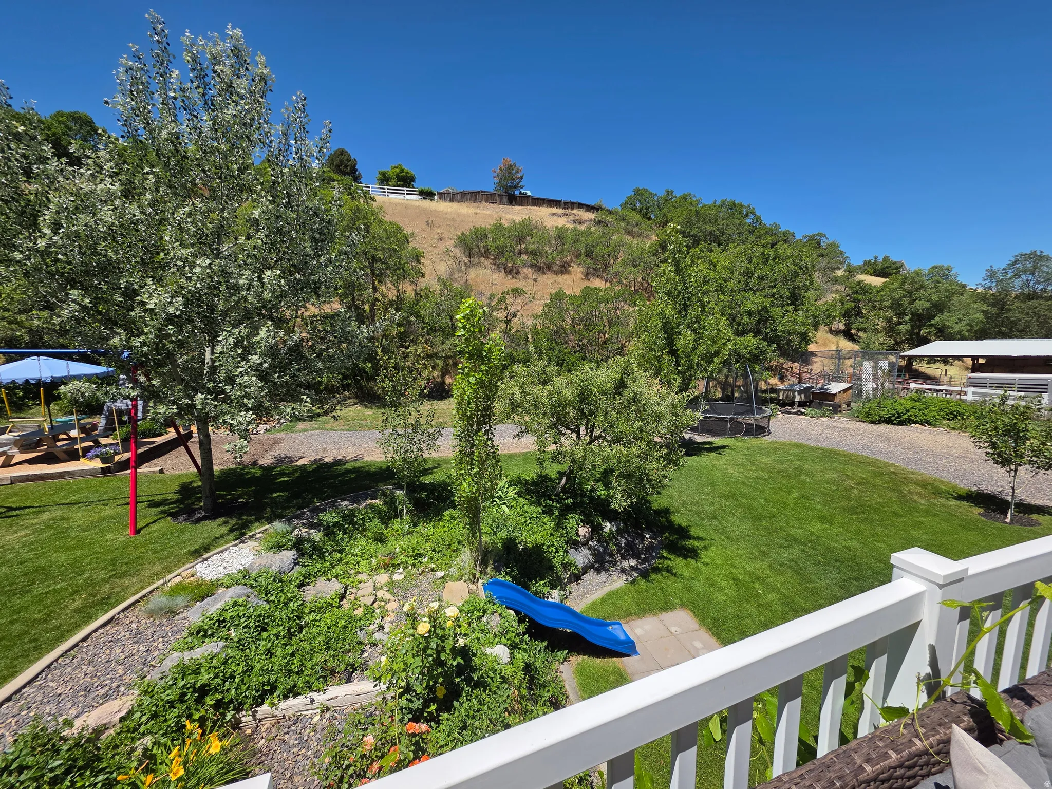Expansive outdoor space featuring a manicured lawn, established trees, and natural landscaping with rock elements