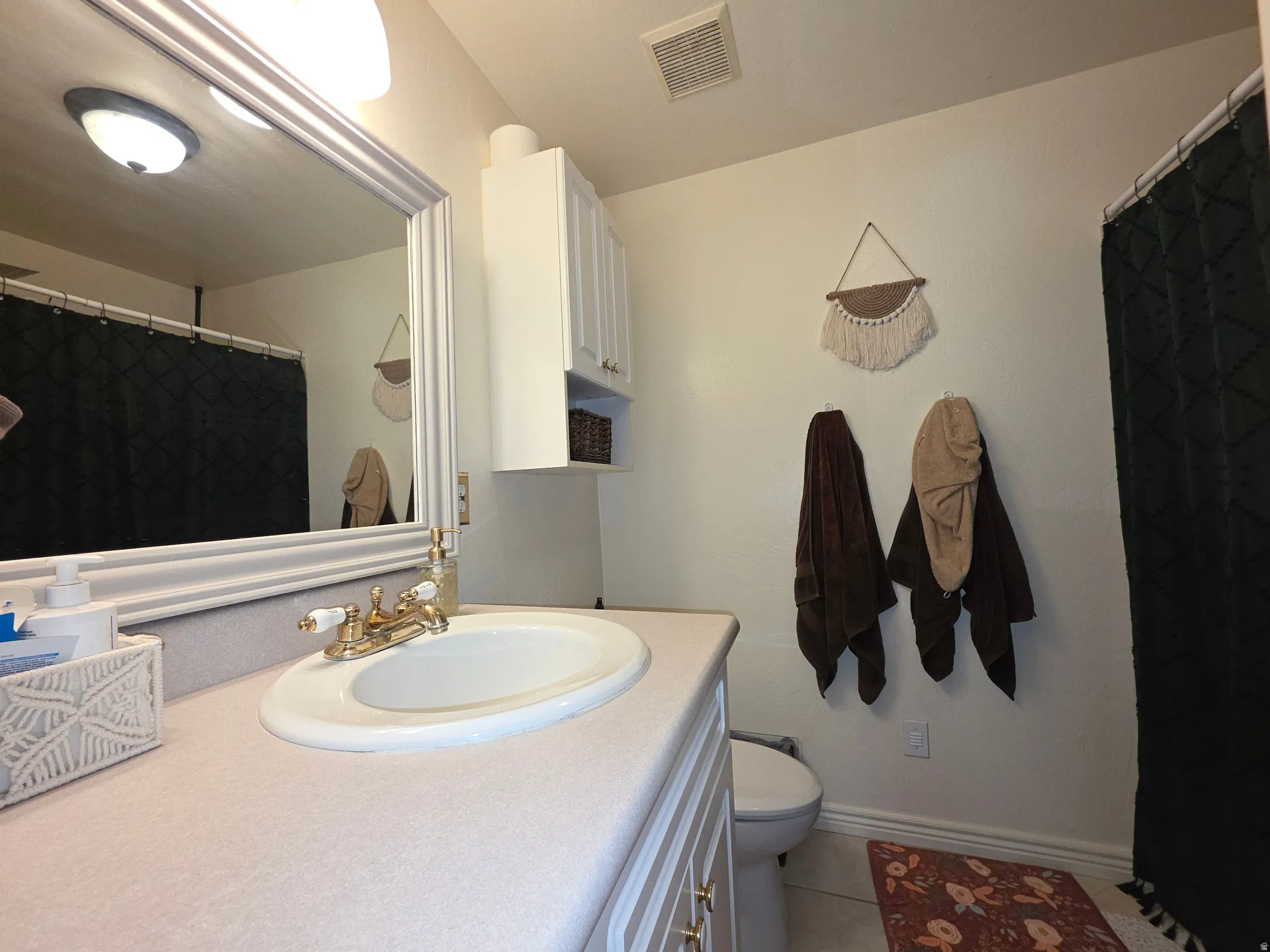Bathroom featuring a vanity with an integrated sink, a large framed mirror, and a wall-mounted storage cabinet