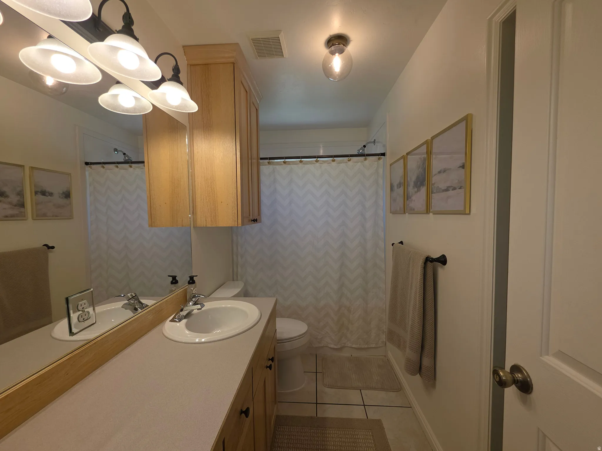 Upstairs Main Bathroom featuring a double vanity with integrated sinks, wood-finish cabinetry, and a large wall-mounted mirror