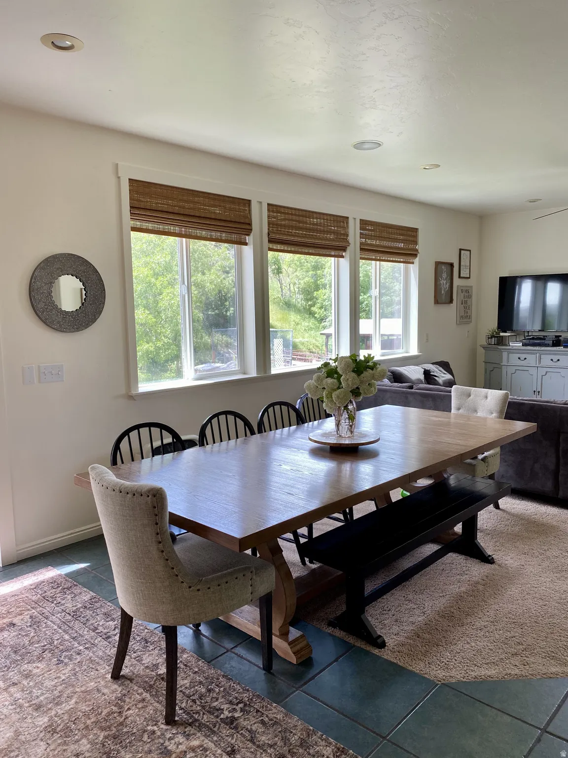 Dining area featuring multiple windows with natural woven shades, recessed lighting, and a blend of tile and carpet flooring
