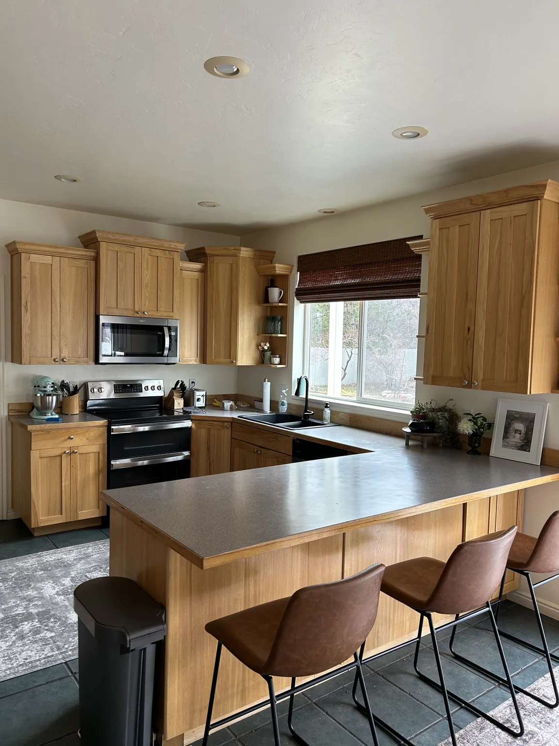 Kitchen with U-shaped counter space, featuring wood cabinetry and an integrated breakfast bar