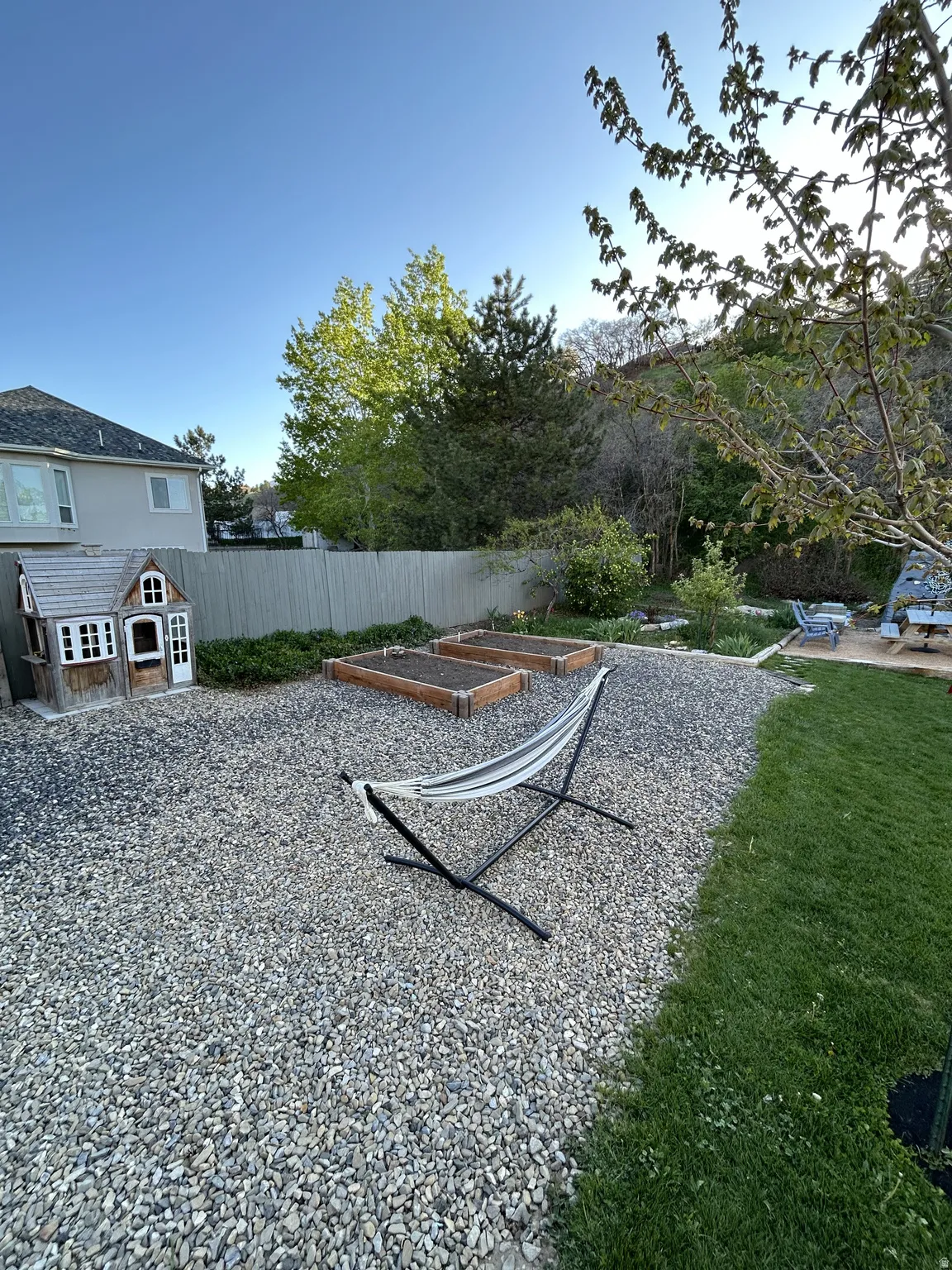 Spacious backyard featuring a gravel patio area with two raised garden beds