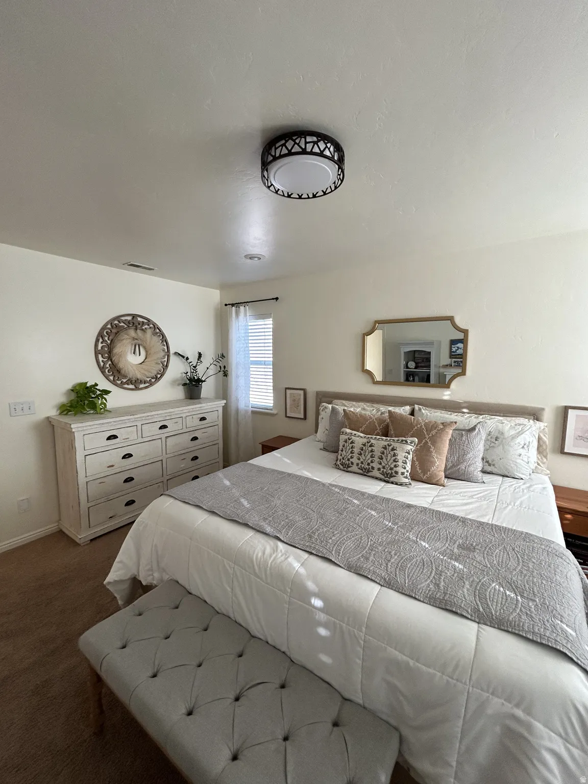 Owner's suite Neutral tone walls with an ornate ceiling fixture and a window with blinds