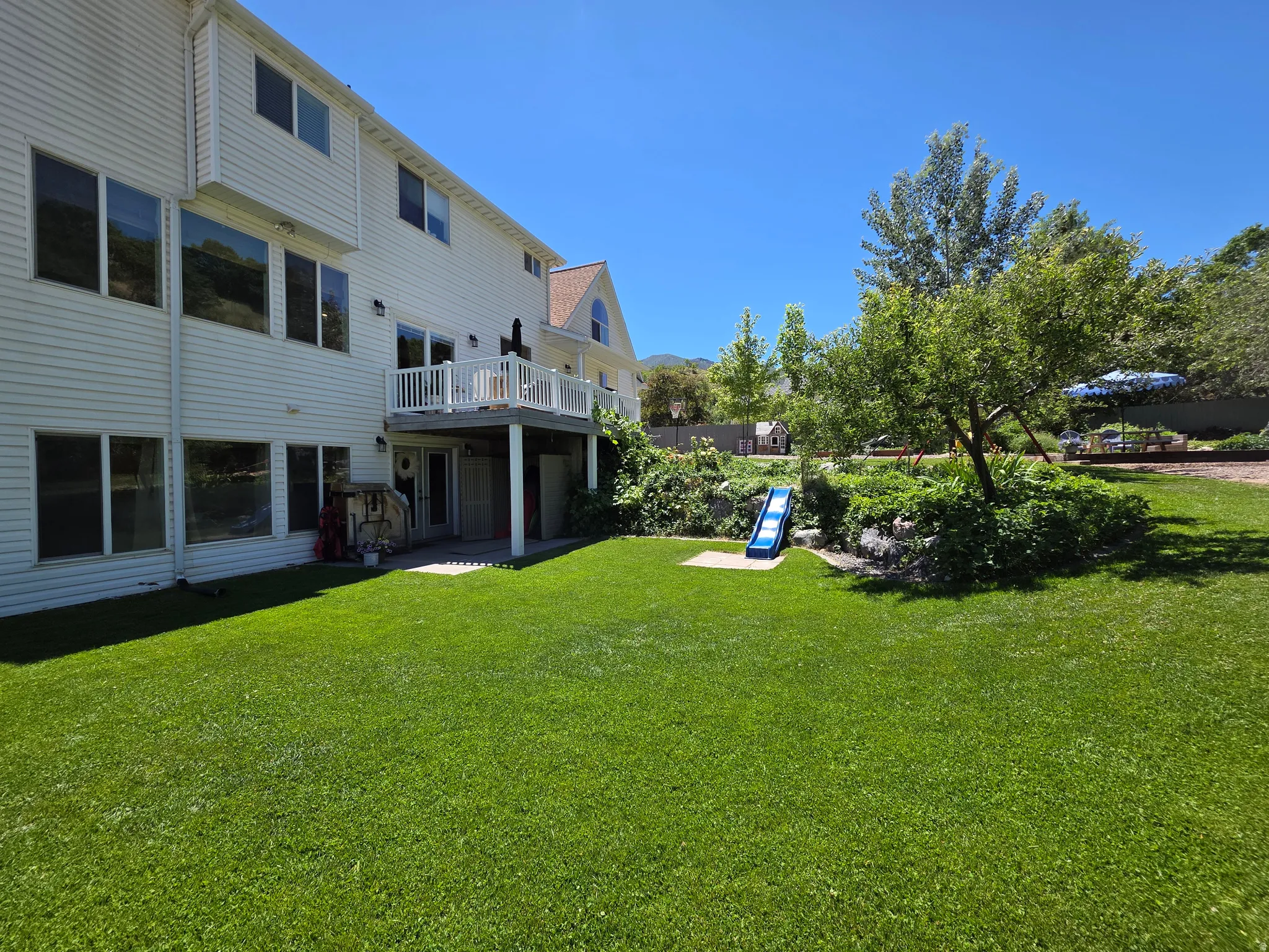 Expansive backyard featuring a large green lawn and mature trees