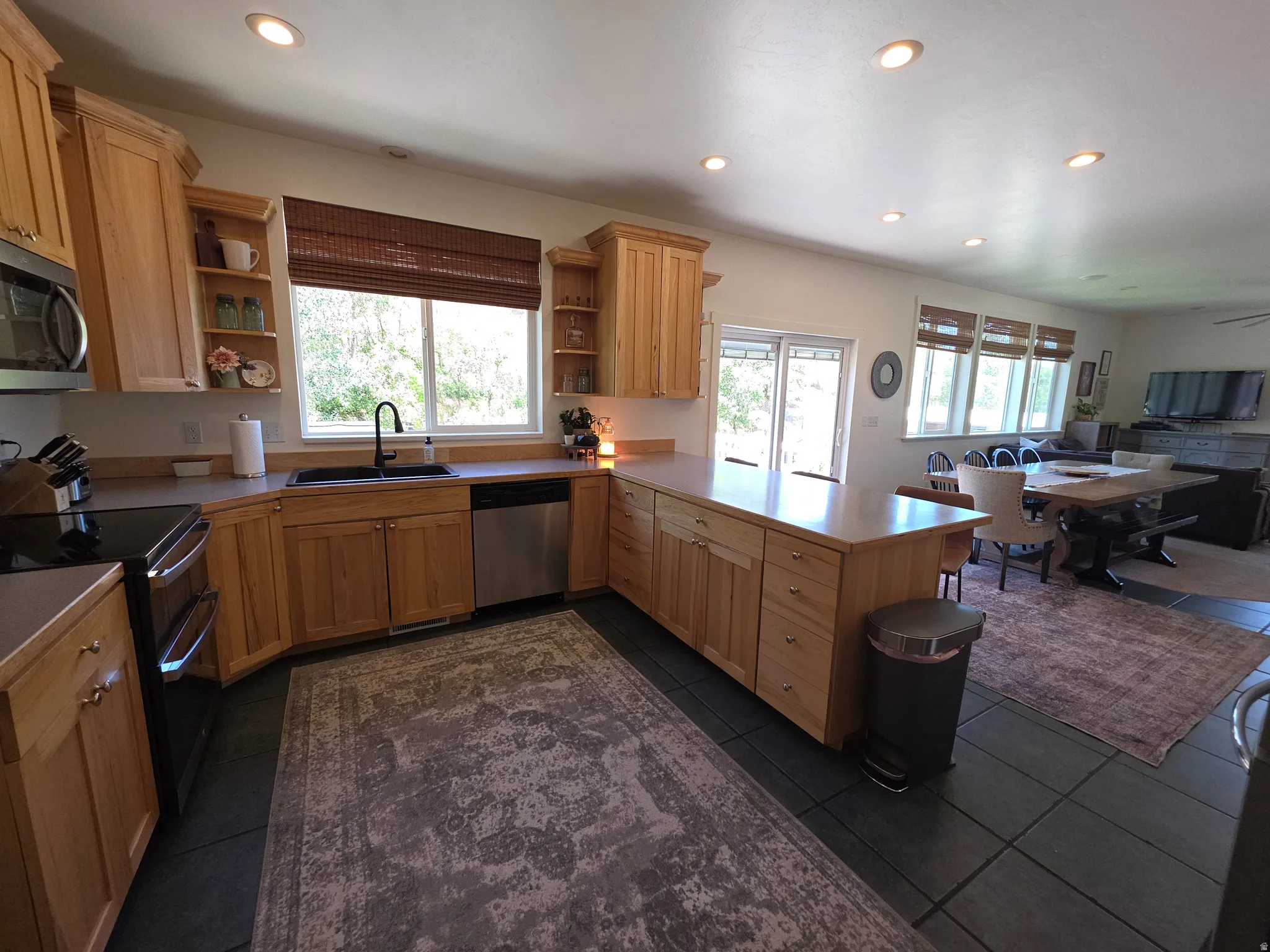 Kitchen featuring light wood cabinetry, stainless steel appliances, dark tile flooring, and recessed lighting