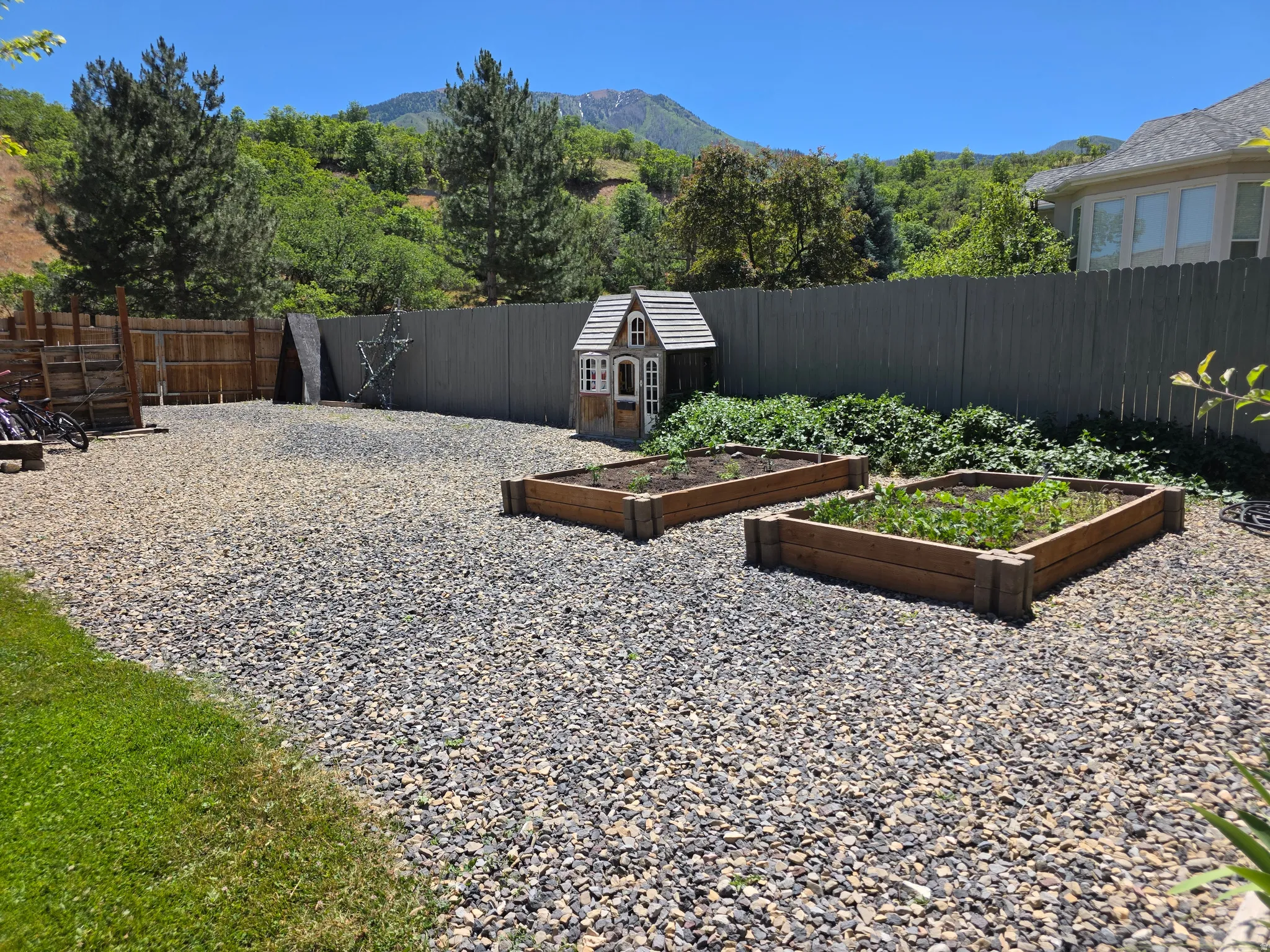 Gravel-covered yard area featuring two raised garden beds