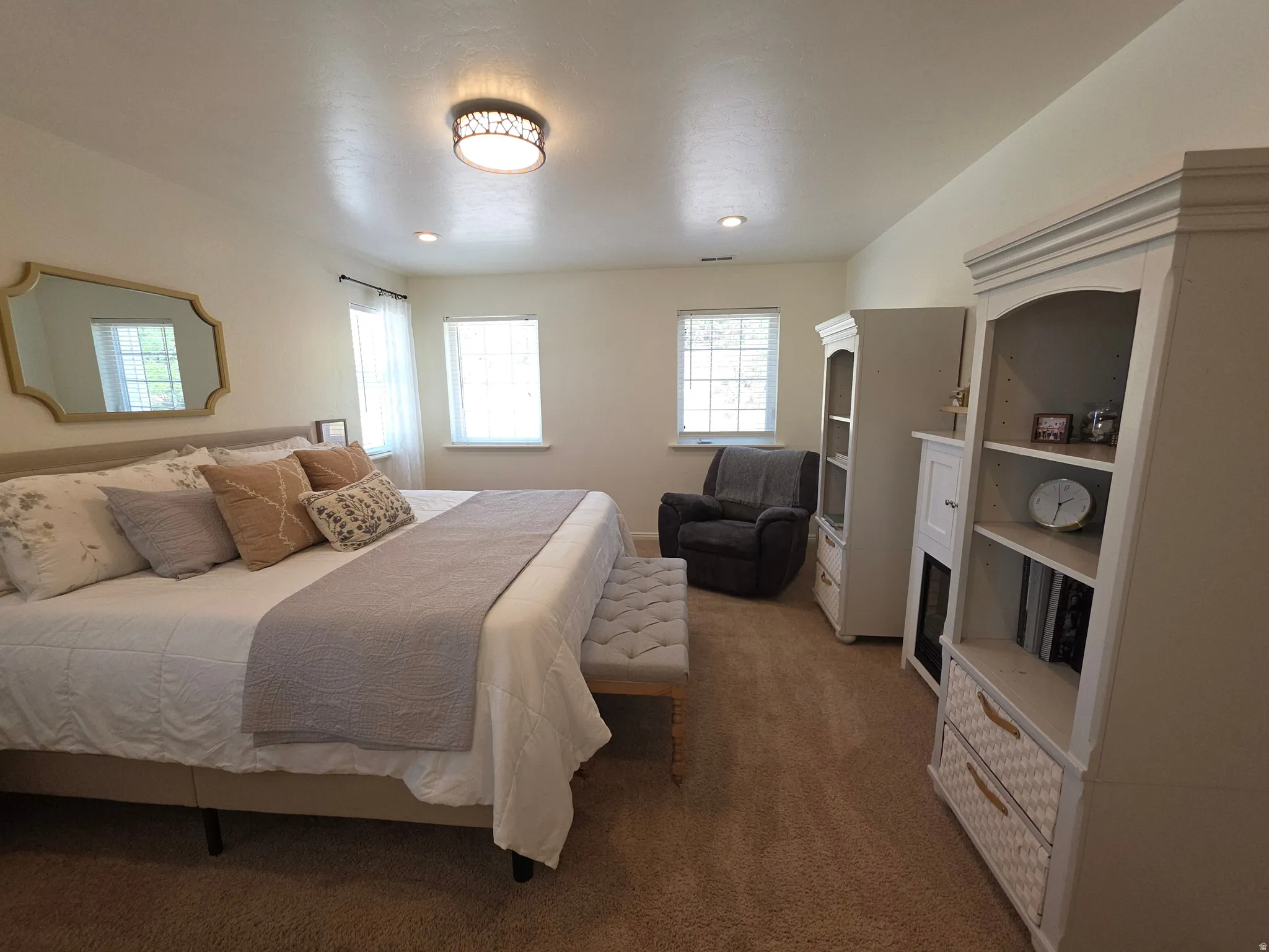 Carpeted bedroom featuring two windows with white blinds, a decorative ceiling light fixture, and recessed lighting