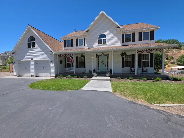 Two-story residence featuring white siding, a covered front porch, and a light brown shingle roof