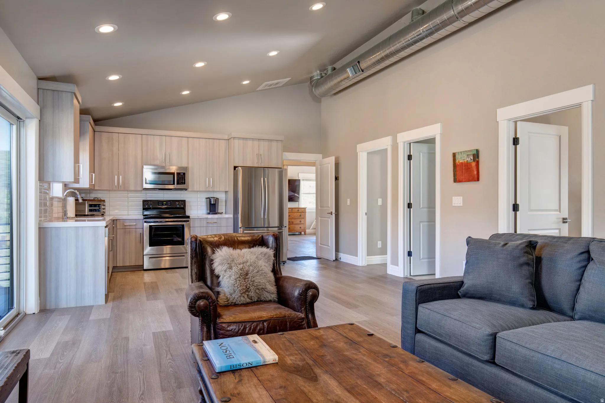 Open-concept living area featuring a vaulted ceiling and exposed ductwork