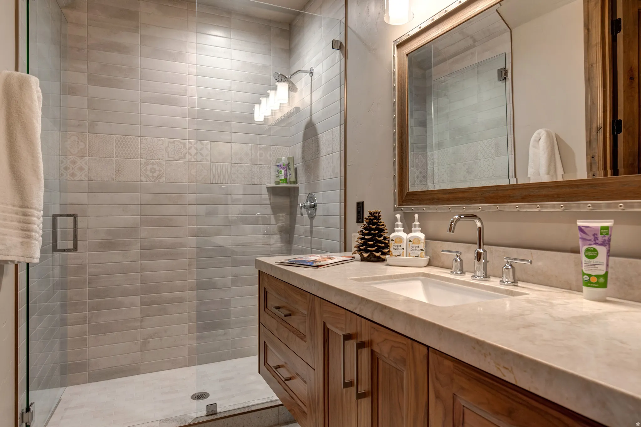 Contemporary bathroom featuring a spacious glass-enclosed shower with horizontal tile work and decorative accent tiles