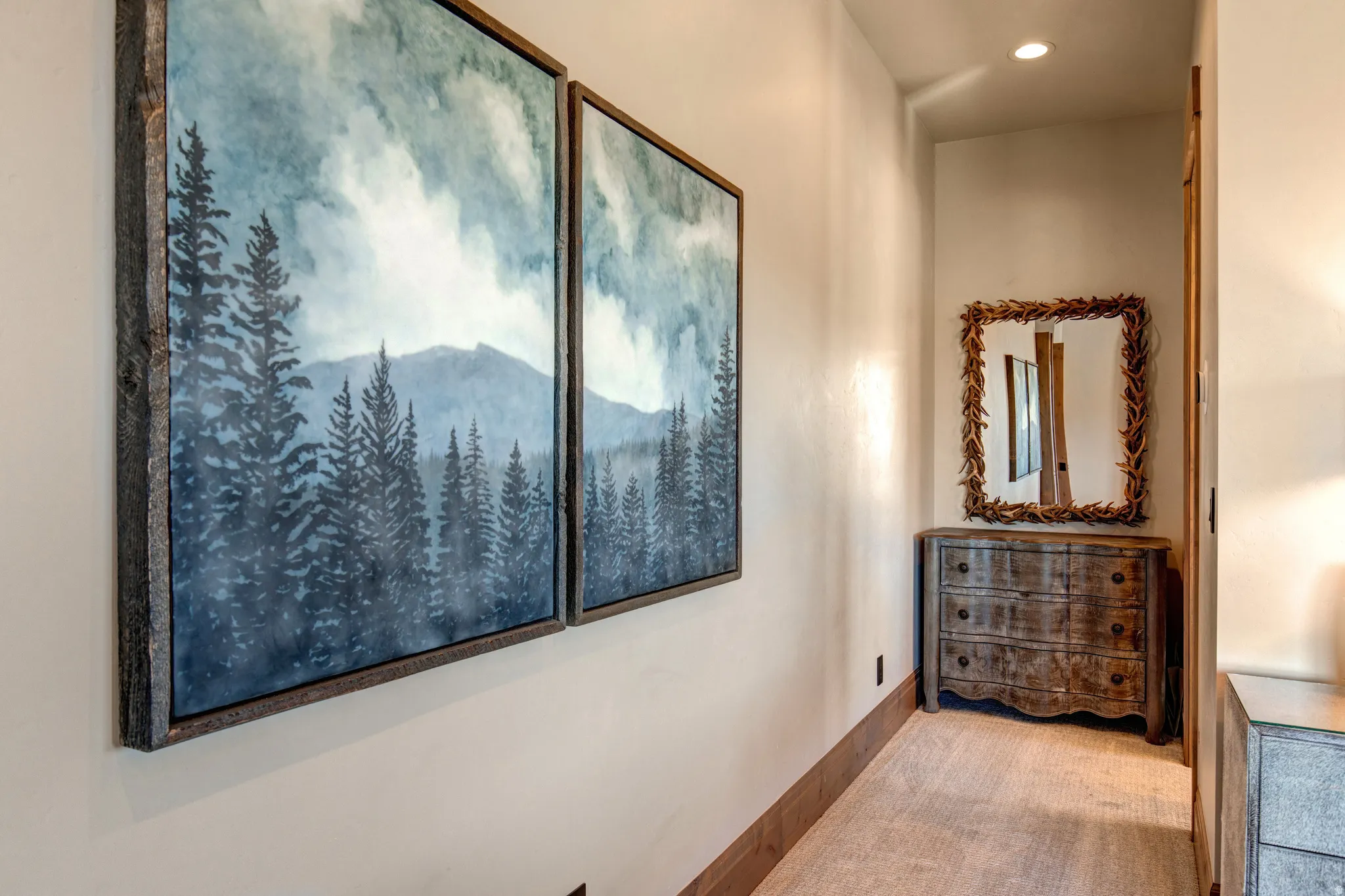 Recessed lighting illuminates a neutral-toned wall with a wood-finish baseboard, complementing the light-colored carpeting