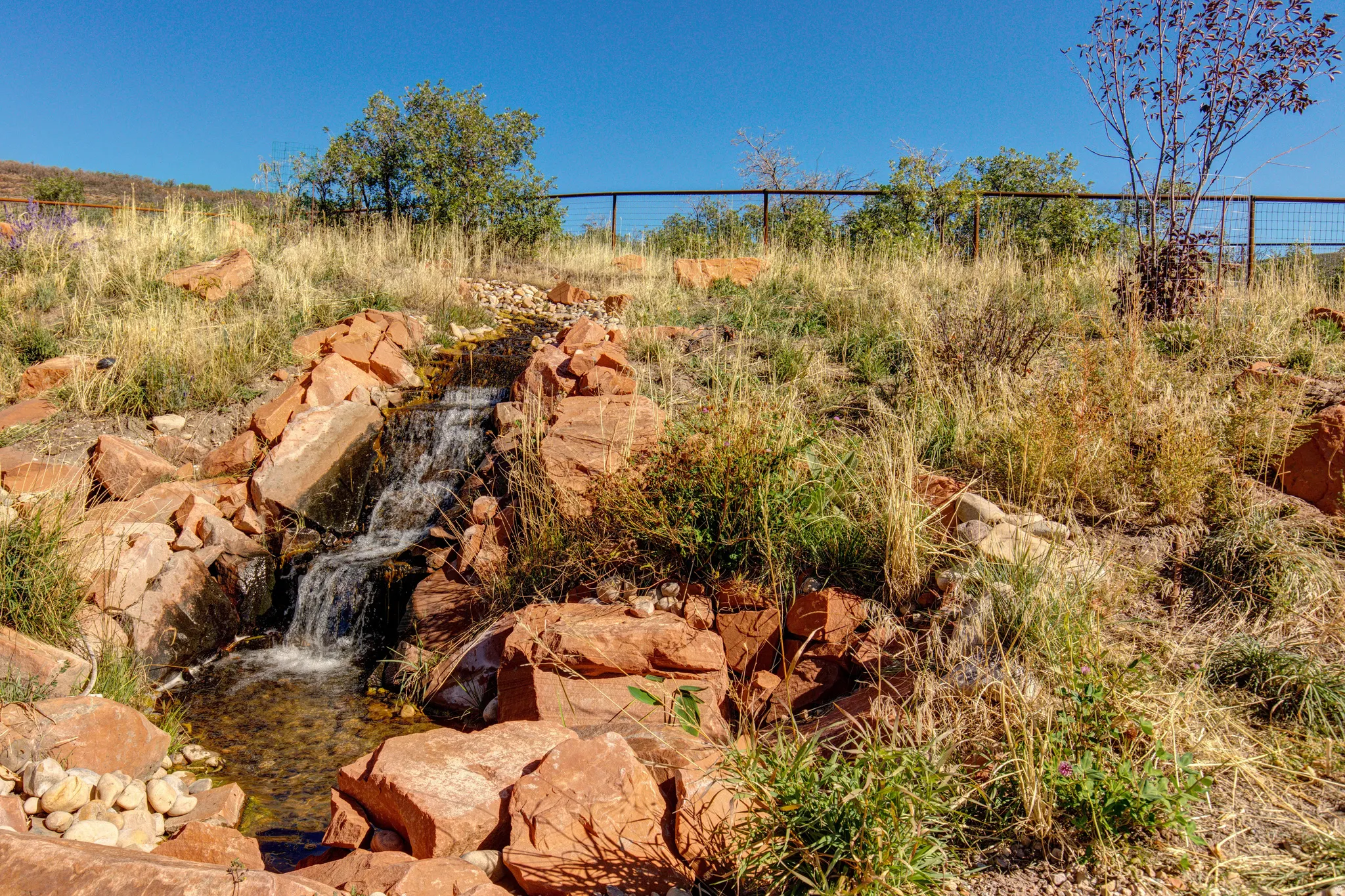 Tiered water feature with natural stone surround, integrated into a landscaped incline