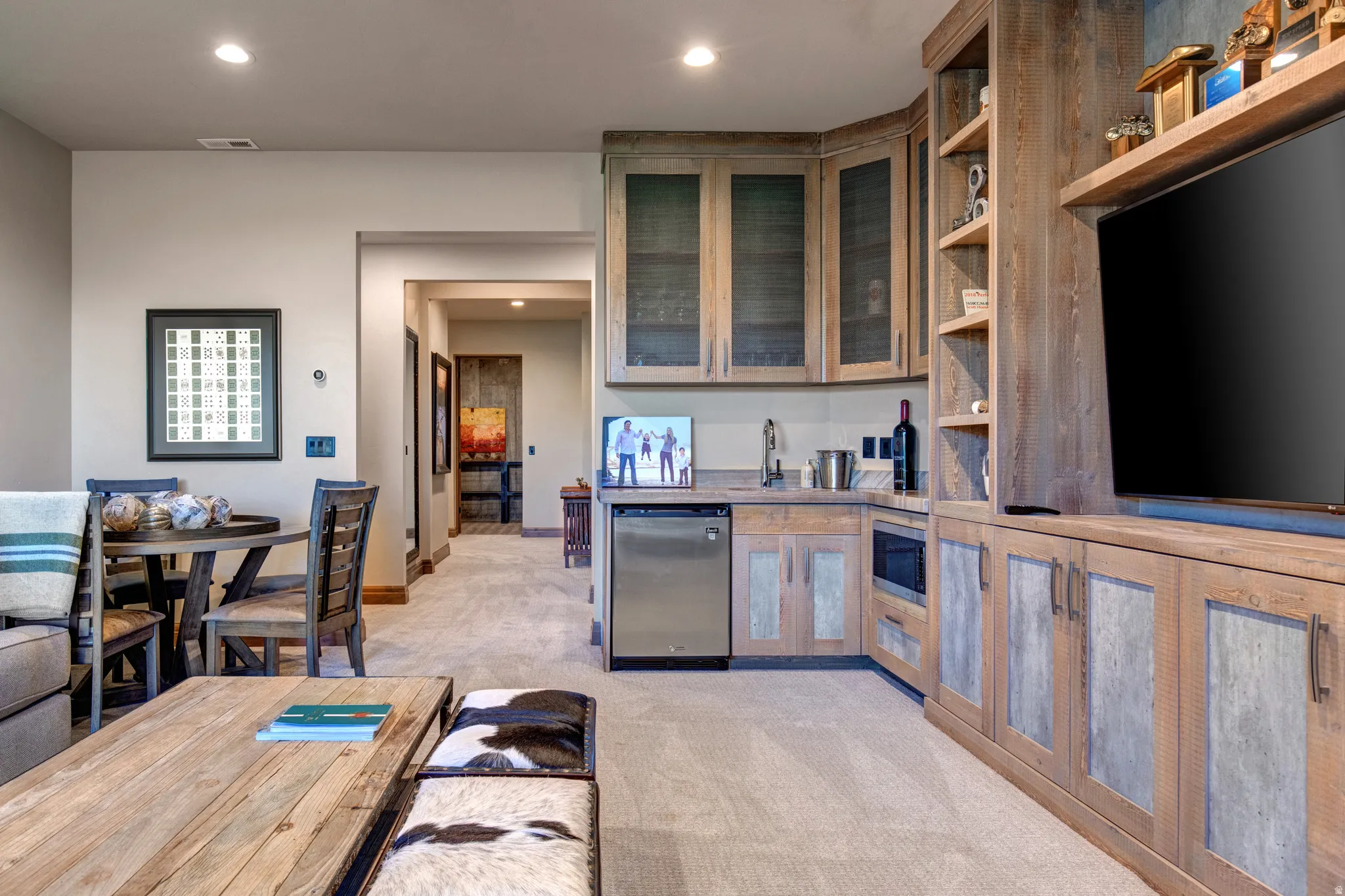 Integrated entertainment area featuring custom wood-finish cabinetry, built-in shelving, a wet bar with a stainless steel sink, and a beverage refrigerator