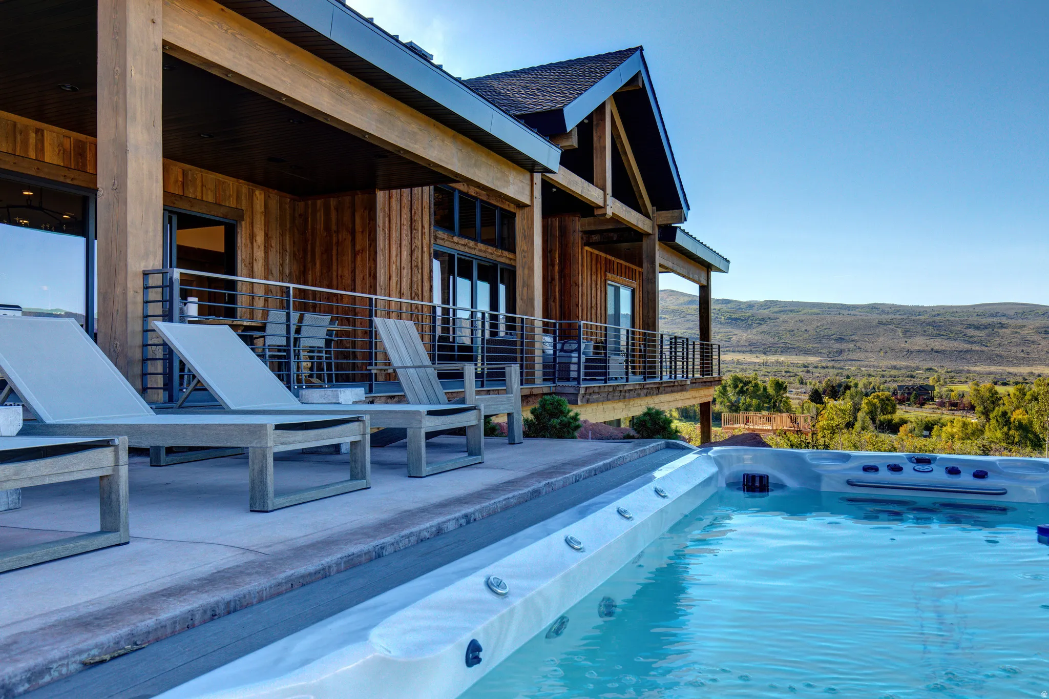 Outdoor patio featuring an integrated hot tub and an infinity-edge pool