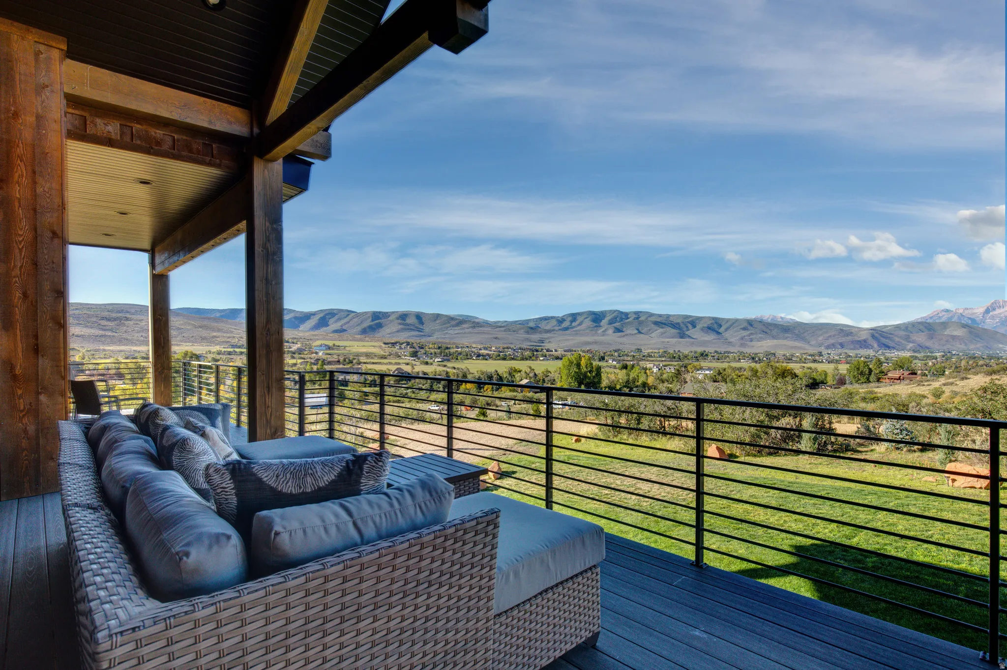 Expansive outdoor deck featuring wood-finish structural beams, black horizontal railings, and composite decking